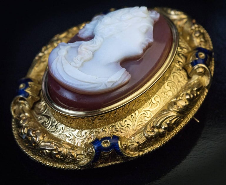 A rare French King Louis Philippe era sardonyx cameo brooch. The cameo is carved in high relief with a classical female bust and set in a large ornate 18K gold and cobalt blue enamel frame. The cameo is dated on the back ‘1842’.

Size of the cameo