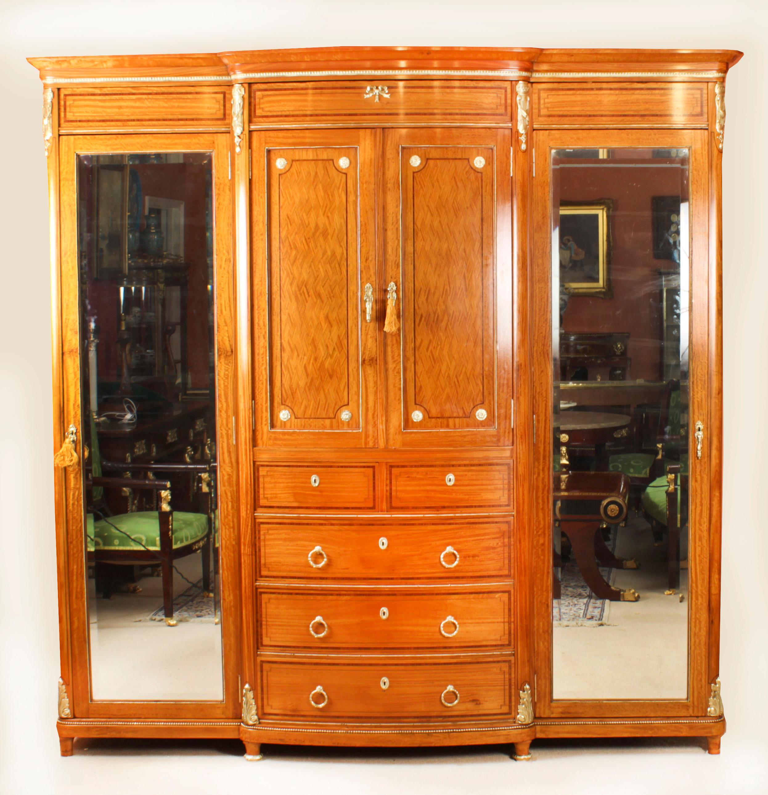 This is a large, rare, and impressive, antique French satinwood, wood banded, parquetry inlaid and ormolu mounted compactum wardrobe, circa 1880 in date.
 
The central section has a pair of panelled cupboard doors superbly inlaid with diamond