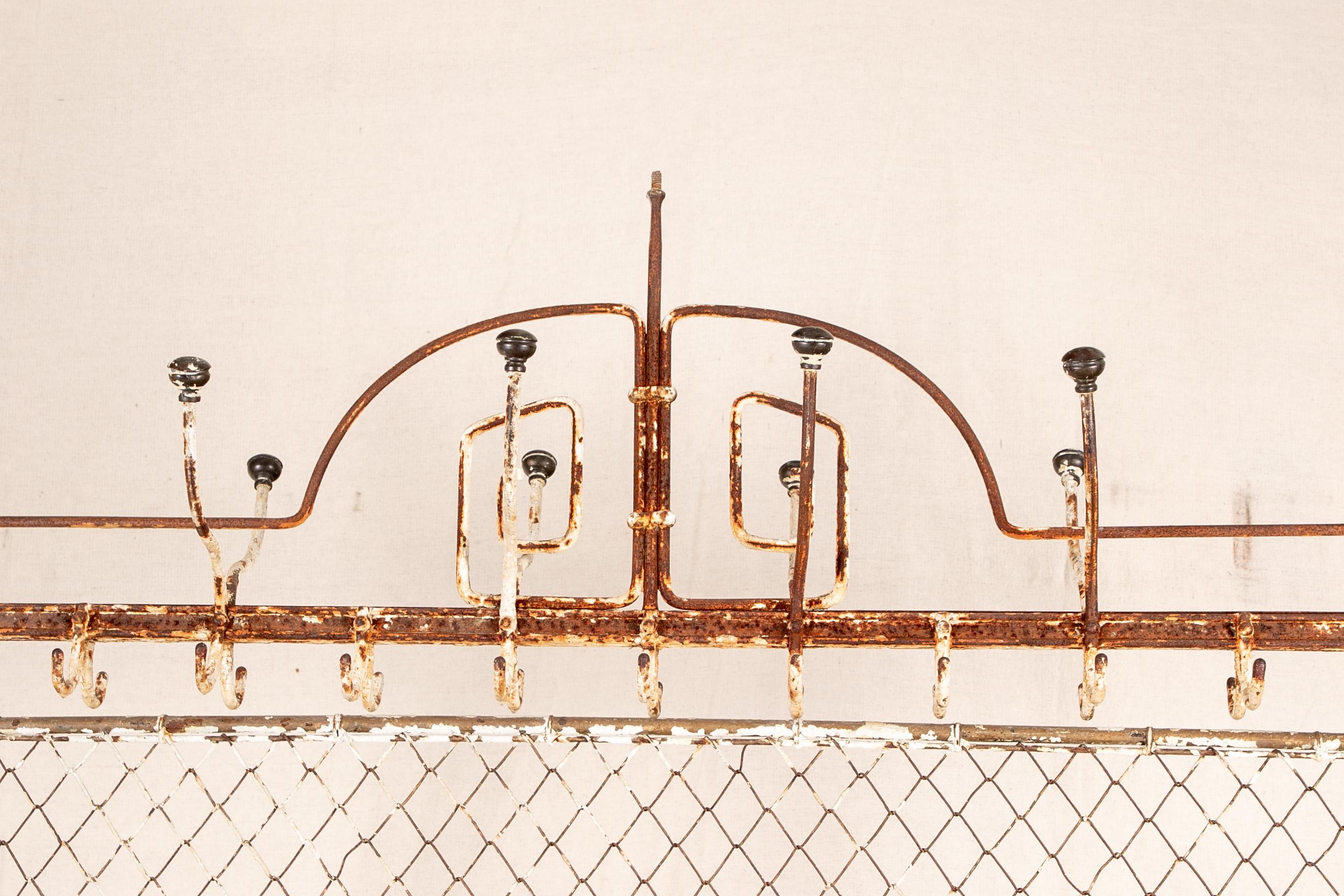 Antique French screen coat rack with hooks, acquired from a Parisian market. Iron in old white paint (many losses). Multiple hooks on top for coats and hats, a centre mesh panel and open lower shelf for umbrellas and canes. An X-form lower support