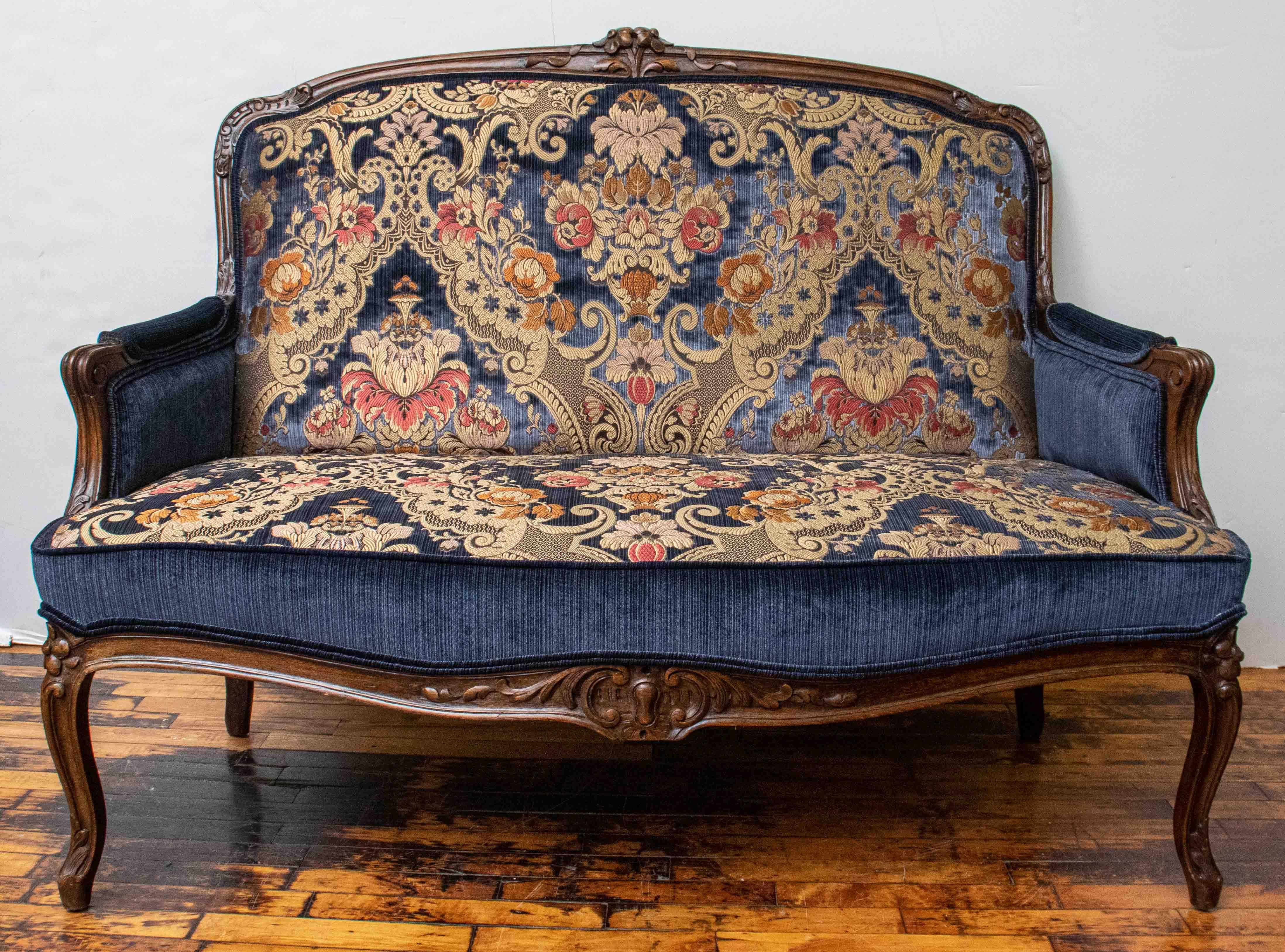 Antique handmade French settee with highly carved walnut wood frame. Recently upholstered in a Scalamandre brocade gold and blue fabric with coordinating blue strie velvet. Excellent antique condition. A real show stopper!