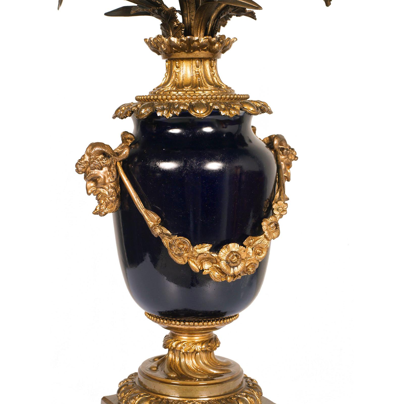 Early XIX Century French candlestick , Sèvres blue cobalt porcelain, gilt bronze  centerpiece
Candle holders immersed in a bouquet of flowers. Bronze structure richly decorated with classical motifs, with two heads of Zeus with ram horns.
