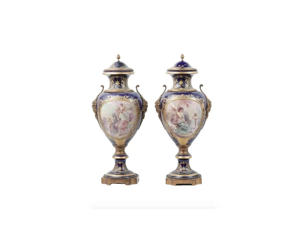 A pair of antique French Sevres gilt bronze mounted porcelain urn vases. The vases are covered with a polychrome enamel, decorated with hand painted symmetrical medallions with the scenes with cherubs and young ladies in the garden on the front, and