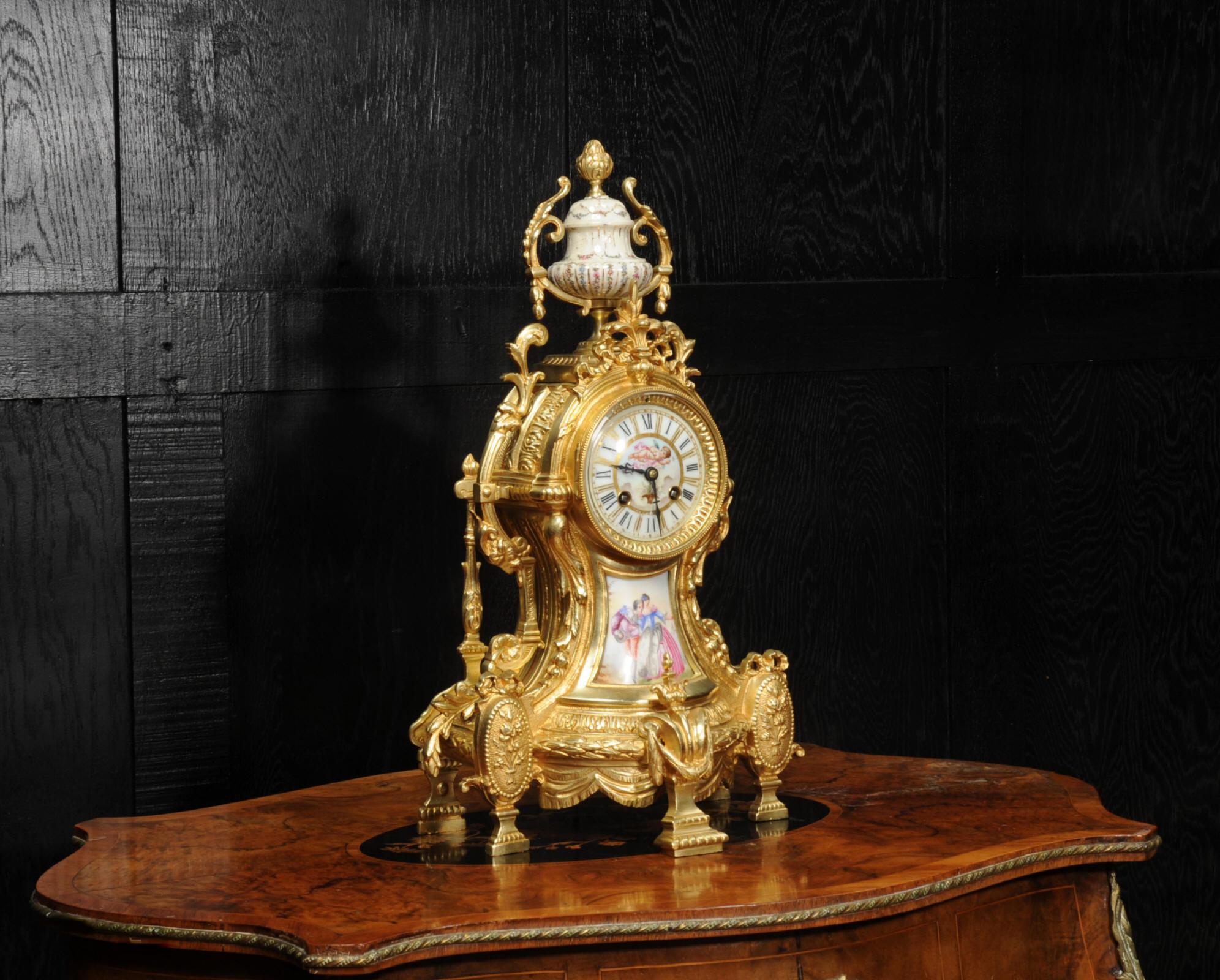 A large and stunning original antique French clock. It is Louis XV in style, mounted with exquisite Sèvres style porcelain with a cream ground. Below the dial is a panel depicting a couple strolling in a country setting. To the top is a gadrooned