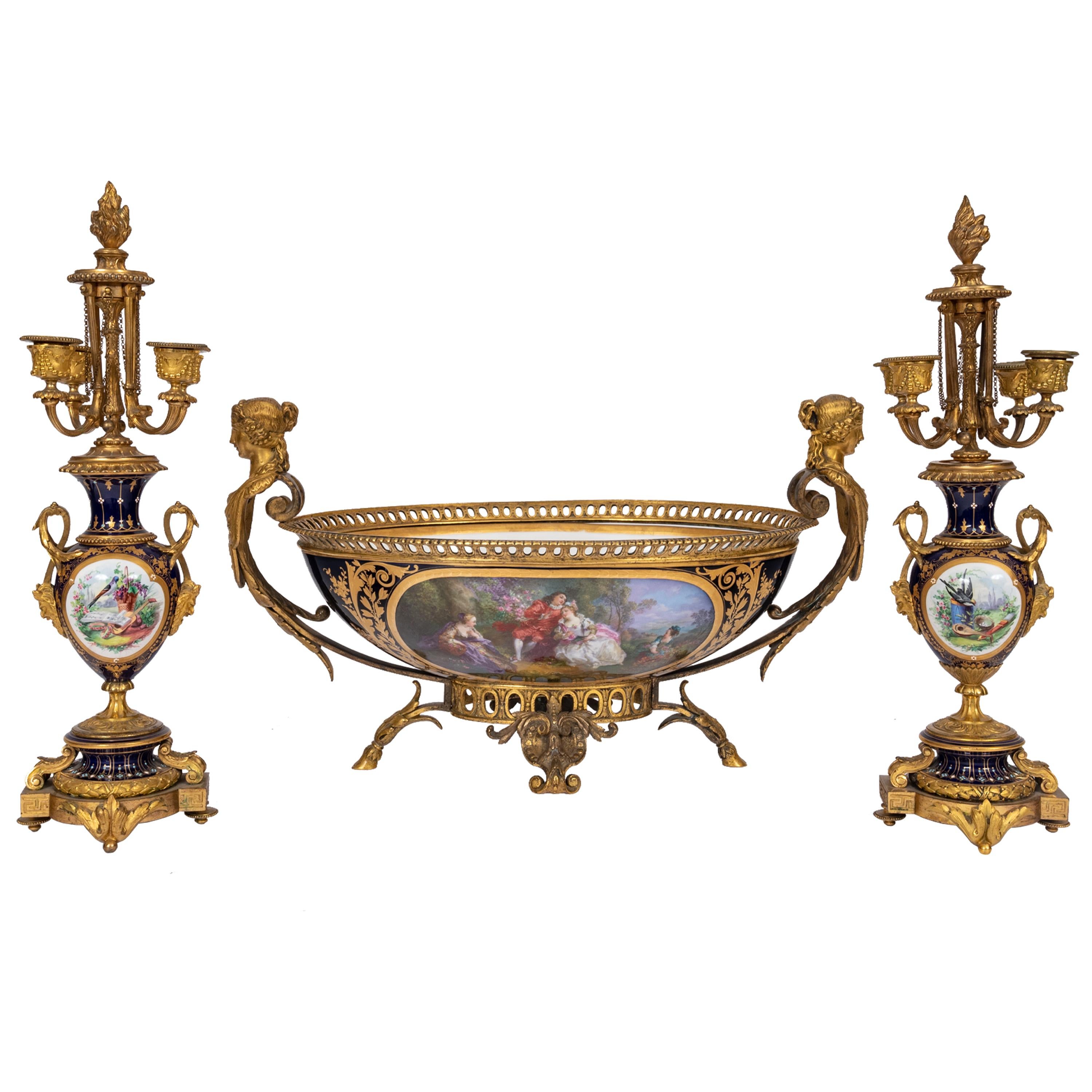 A fine & large antique 'Sevres' porcelain three piece garniture, circa 1880.
The garniture comprising a pair of candelarbra and a large jardiniere centerpiece, each candelarbrum having four branches decorated with garlands and chains, to the top a