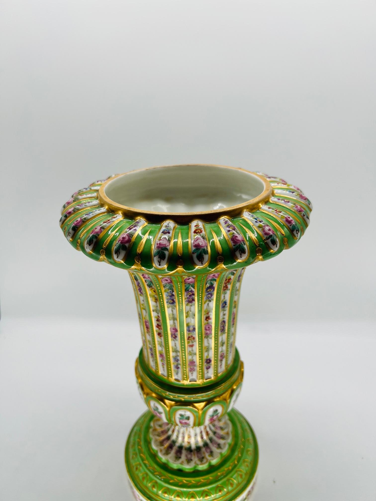 Sevres (French, founded 1756), marked for 1770.

An antique French porcelain urn or vase decorated with a green porcelain base, white ground windows featuring heavy floral decorations and separated by fine gold bead work. The top with gold swag