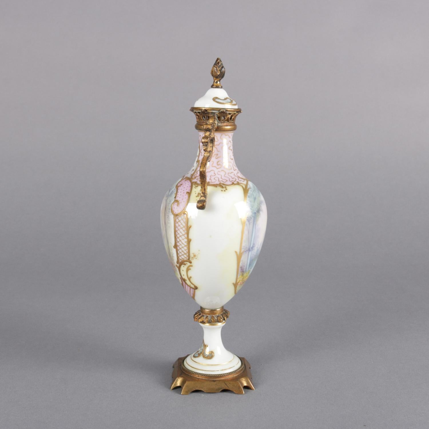 Antique French Sèvres School porcelain lidded urn features hand painted reserves with portrait of woman and landscape scenes, gilt decorated throughout and with bronze mounts, 19th century.

Measures: 8.5