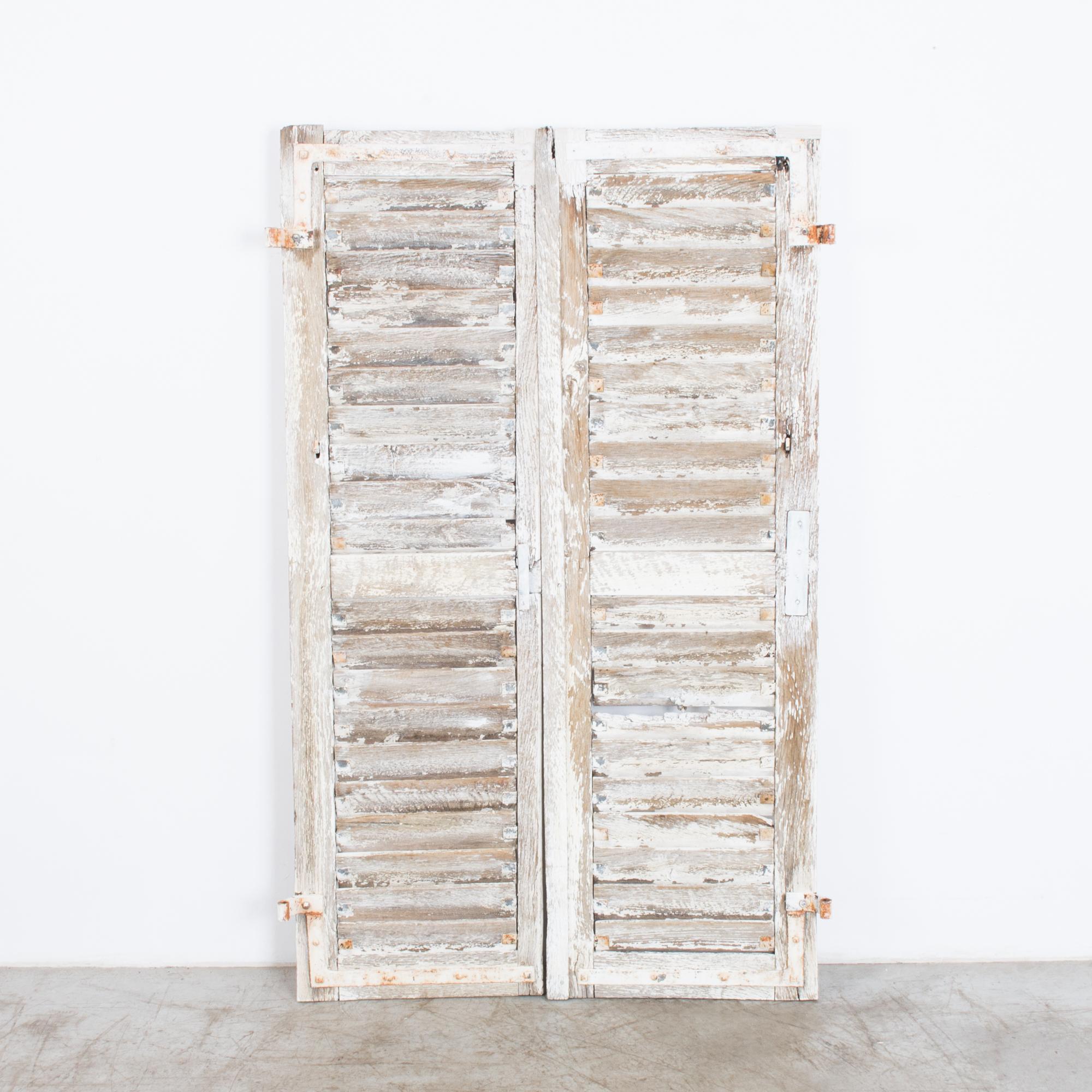 A protective cover from the breezy French countryside. For a space craving character, these charming shutters are layered with worn white paint, creating a beautiful encrusted patina. High contrast textures match with honest material a striking