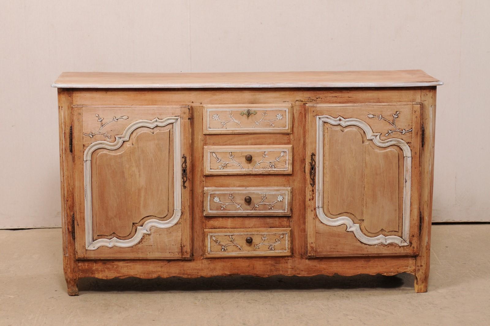 A French carved and bleached wood sideboard cabinet from the early 19th century. This antique console from France features a slightly overhanging and rounded edge top, which rests above a case which houses a pair of decoratively paneled doors