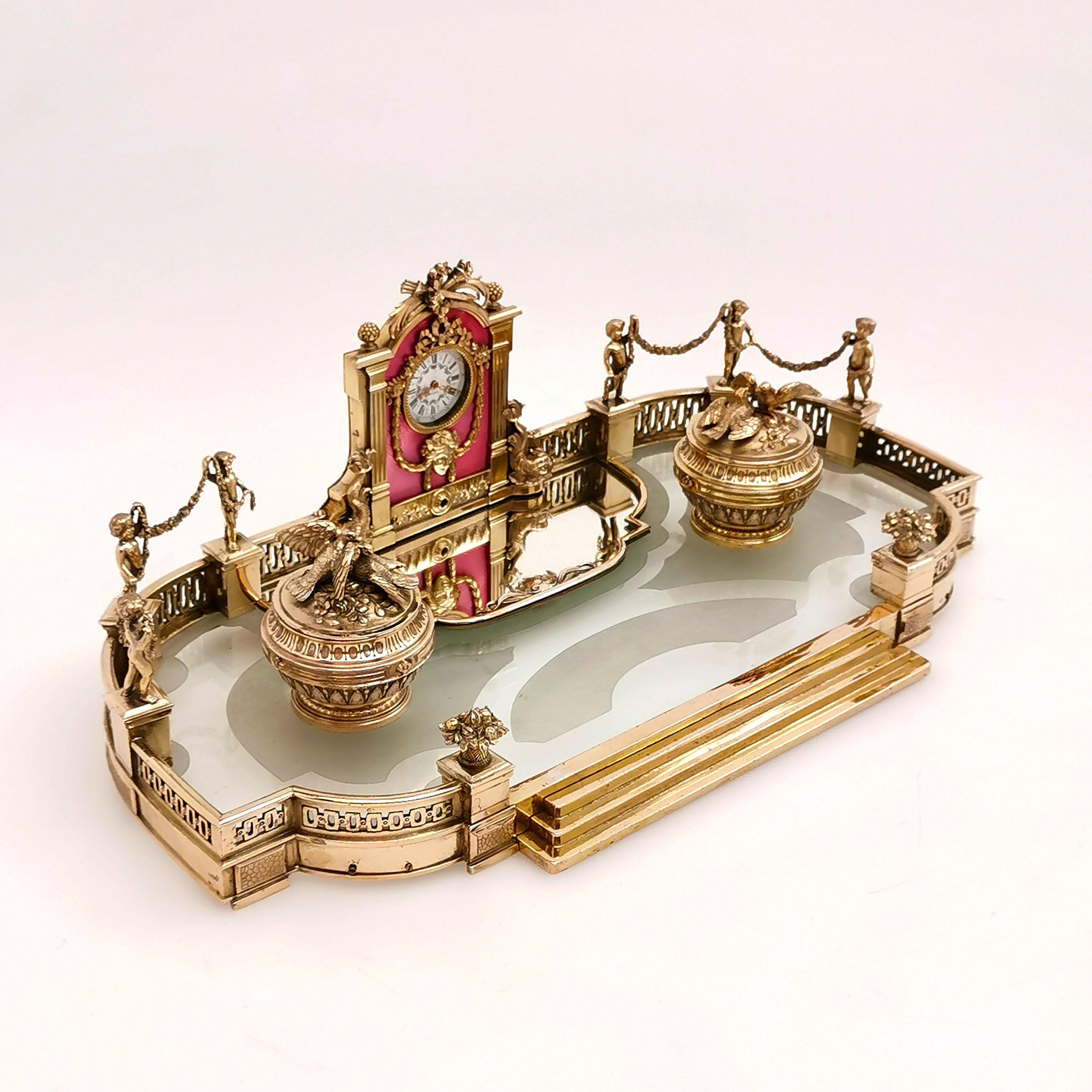 A magnificent antique French silver gilt mounted inkstand with a glass base. The inkstand is created to mirror a baroque or French formal garden, with the gilt & enamel clock in place of water feature. The Clock has a mirror below it and is