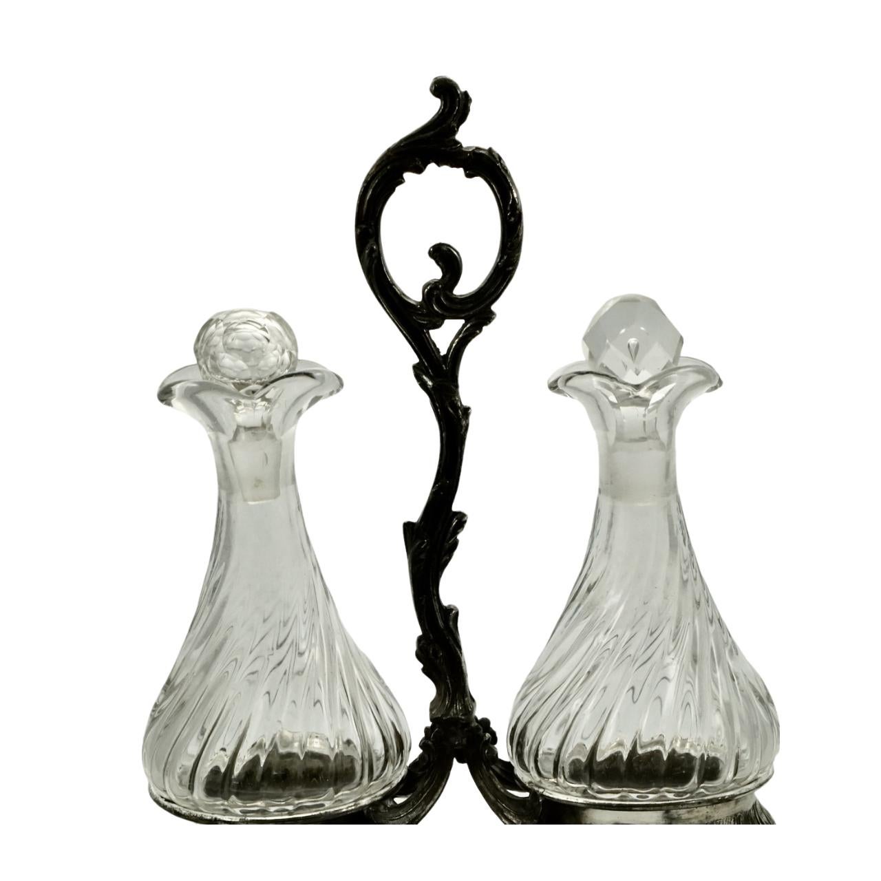 Antique French silver plated serving condiment set. There is an ornate centre handle with two engraved condiment holders standing on feet. The glass bottles are shaped to fit the holders. Measuring width 16.5cm / 6.5 inches, height 24.8 cm / 9.7