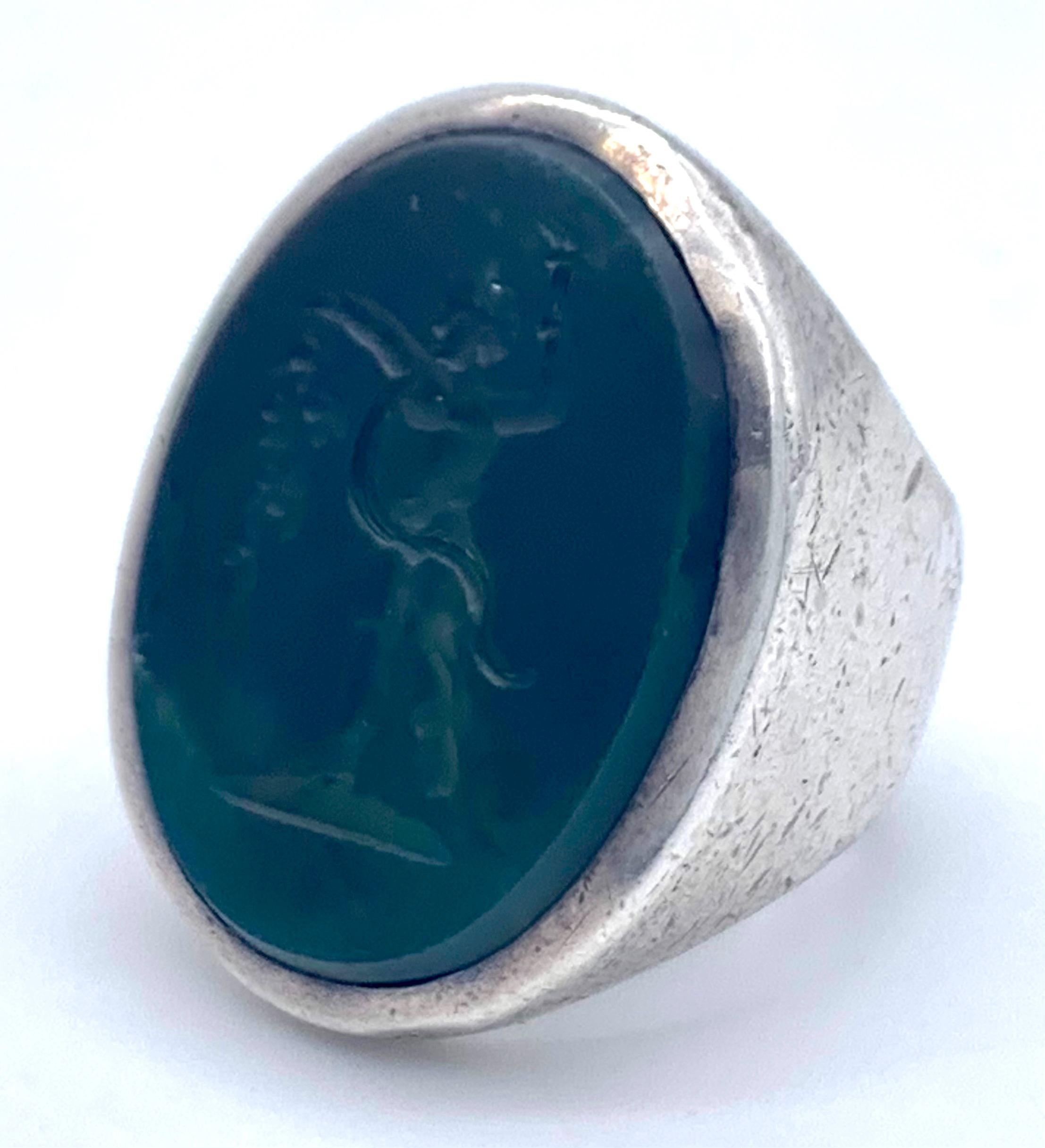 This substantial silver ring holds an intaglio of a follower of the greek god Dyonisos, the god of wine dance and fertility.
The dancing little boy holds a bunch of grapes in his in his left hand, in his right raised hand he is holding a torch.
The