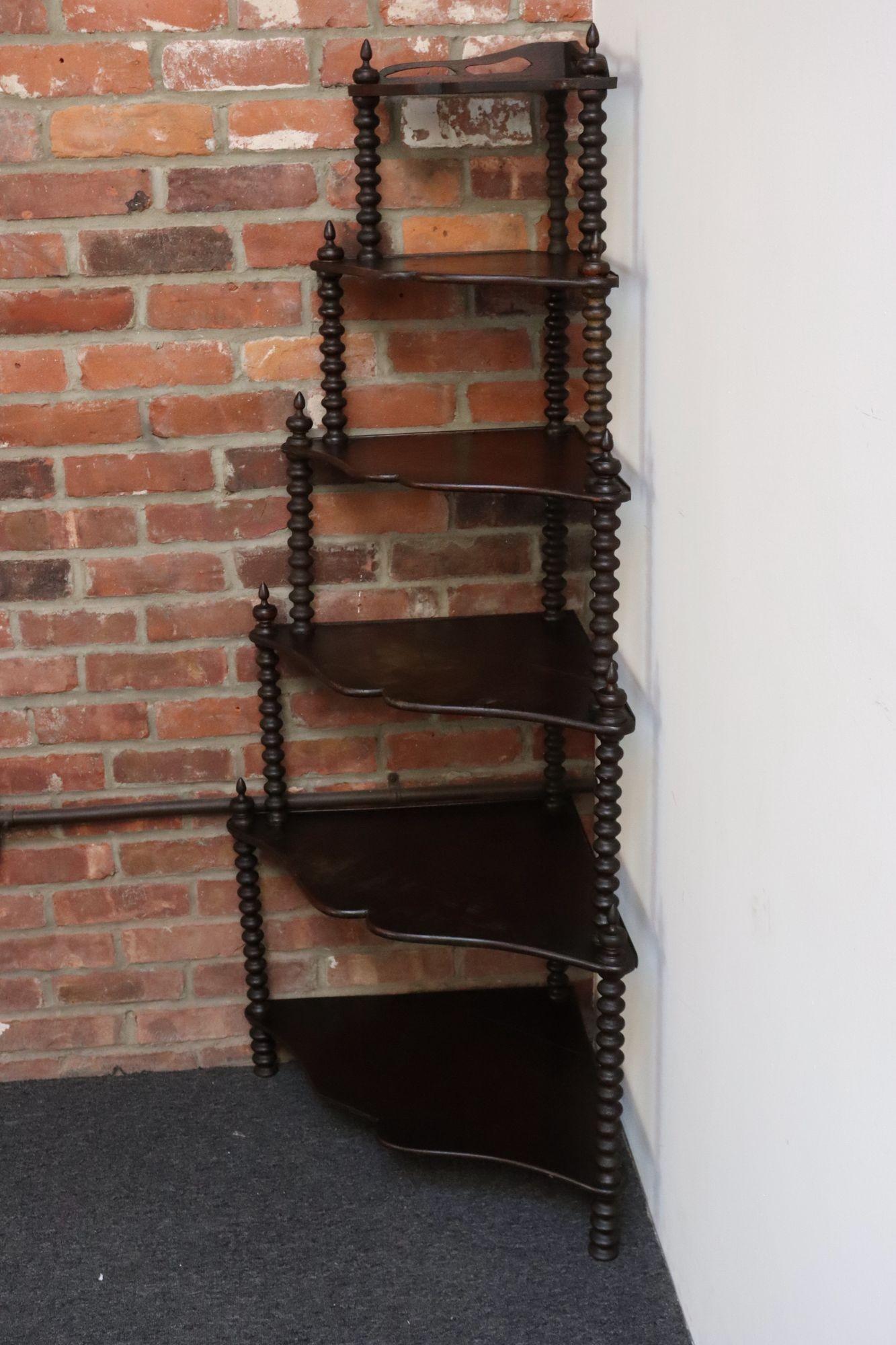 Etagère d'angle en acajou teinté avec des montants en bois tourné en forme de bobine/bobine supportant six niveaux en forme de moustache (vers le début du 20e siècle, France).
L'étagère inférieure présente une perte au niveau du bord avant, comme