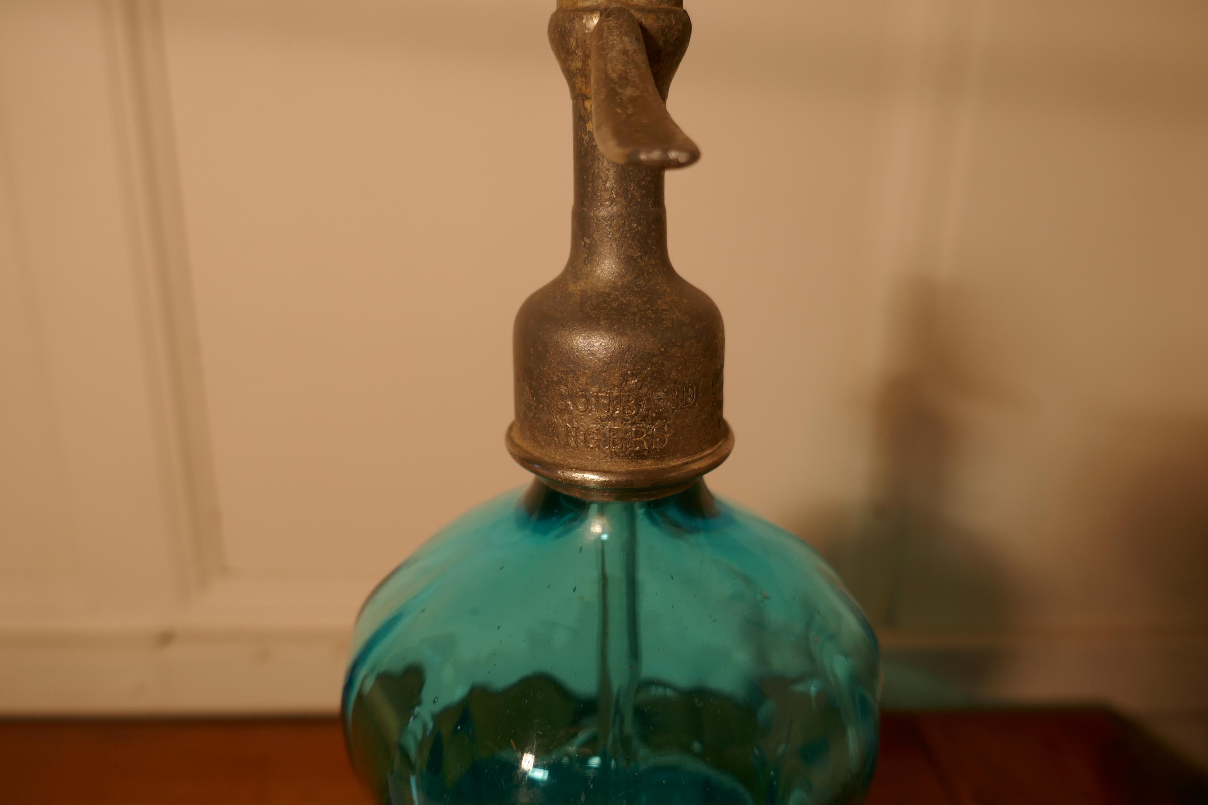 Antique French soda syphon blue glass from Angers, Loire.

Great looking piece
Blue glass etched writing

EAUX GAZUSES
E TOUBARD
ANGERS

Also stamped to trigger. 
Full size and superb thick blown glass waisted shaped with a chip to the