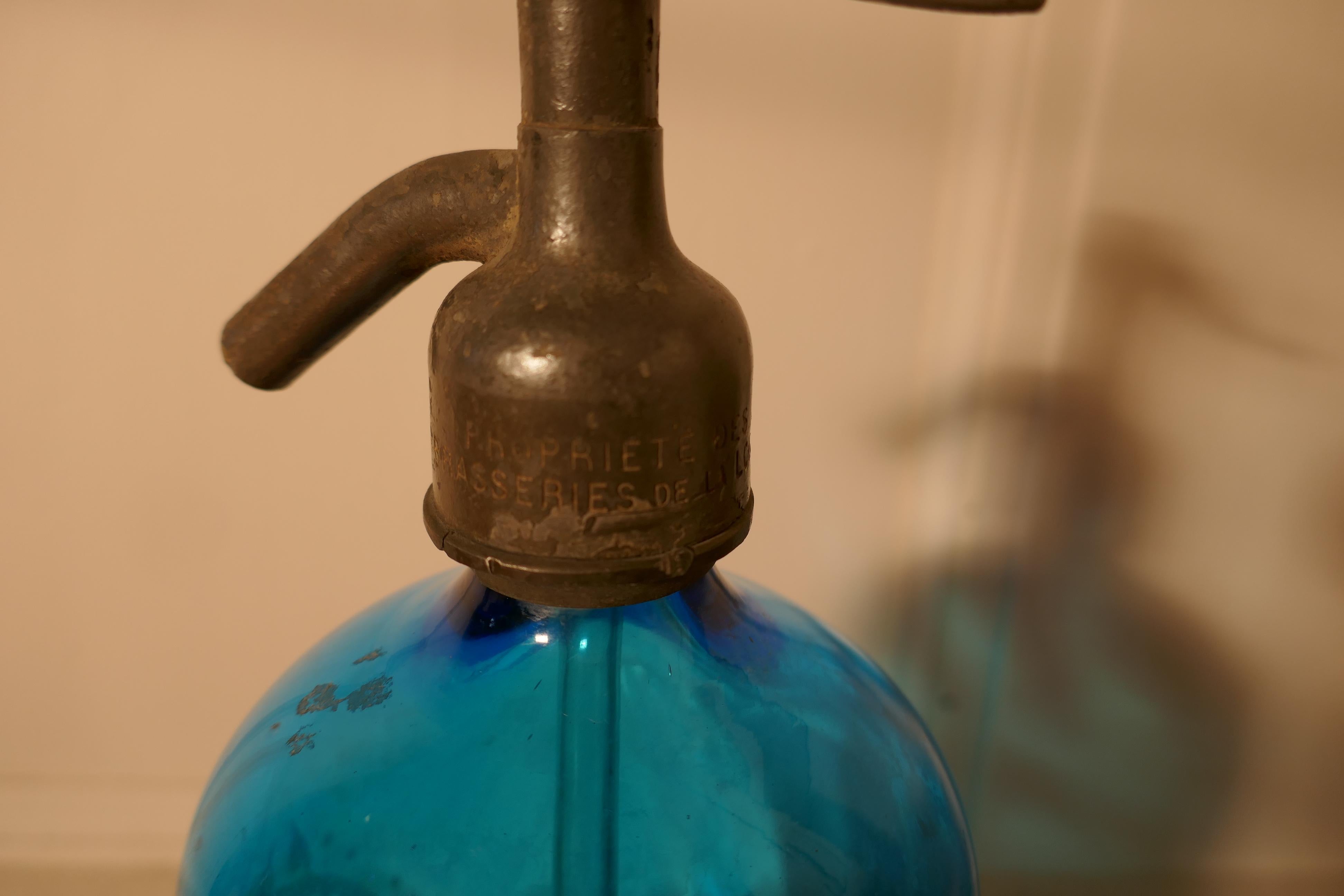 Antique French soda syphon blue glass from St Etienne, Loire

Great looking piece
Blue glass etched writing

SOCIETE DES ELYSEE BARS
ST ETIENNE (LOIRE)


Also stamped to trigger. 
Full size and superb thick blown glass with a slight