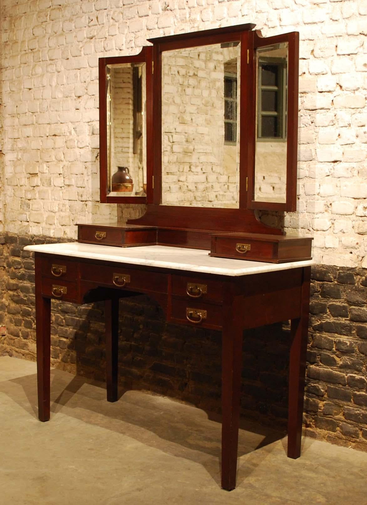 A very elegant dressing table that was made in France in the early 1900s. 
The table has a white Carrara top with a beveled edge. The table base has a central drawer flanked by two drawers on either side. The drawers have a solid oak interior and