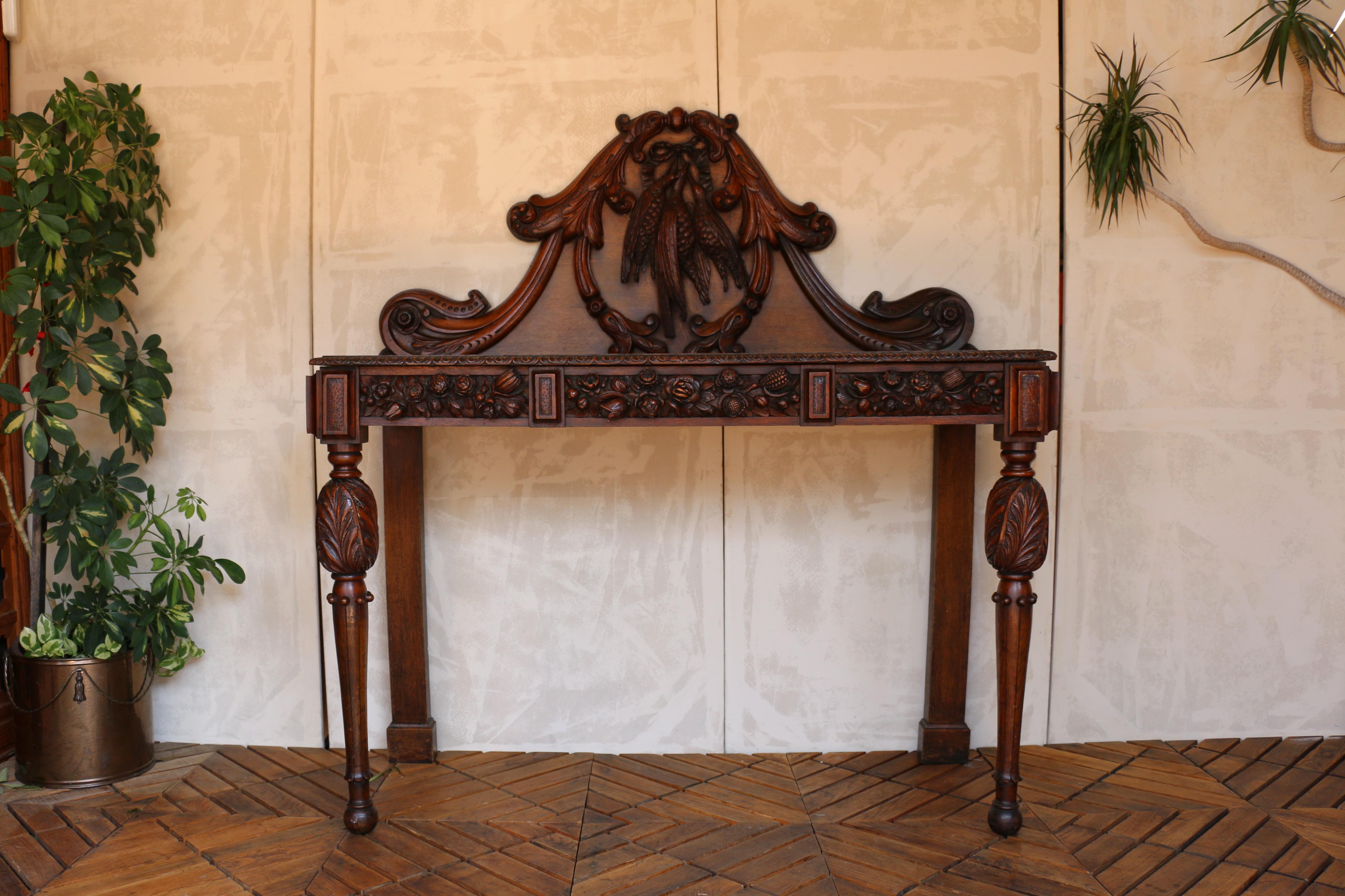 An exquisite console or hall table crafted from solid oak, showcasing the rich detailing of French design. This remarkable piece features a grand high back adorned with deeply carved motifs, including a trio of suspended birds and flowing acanthus