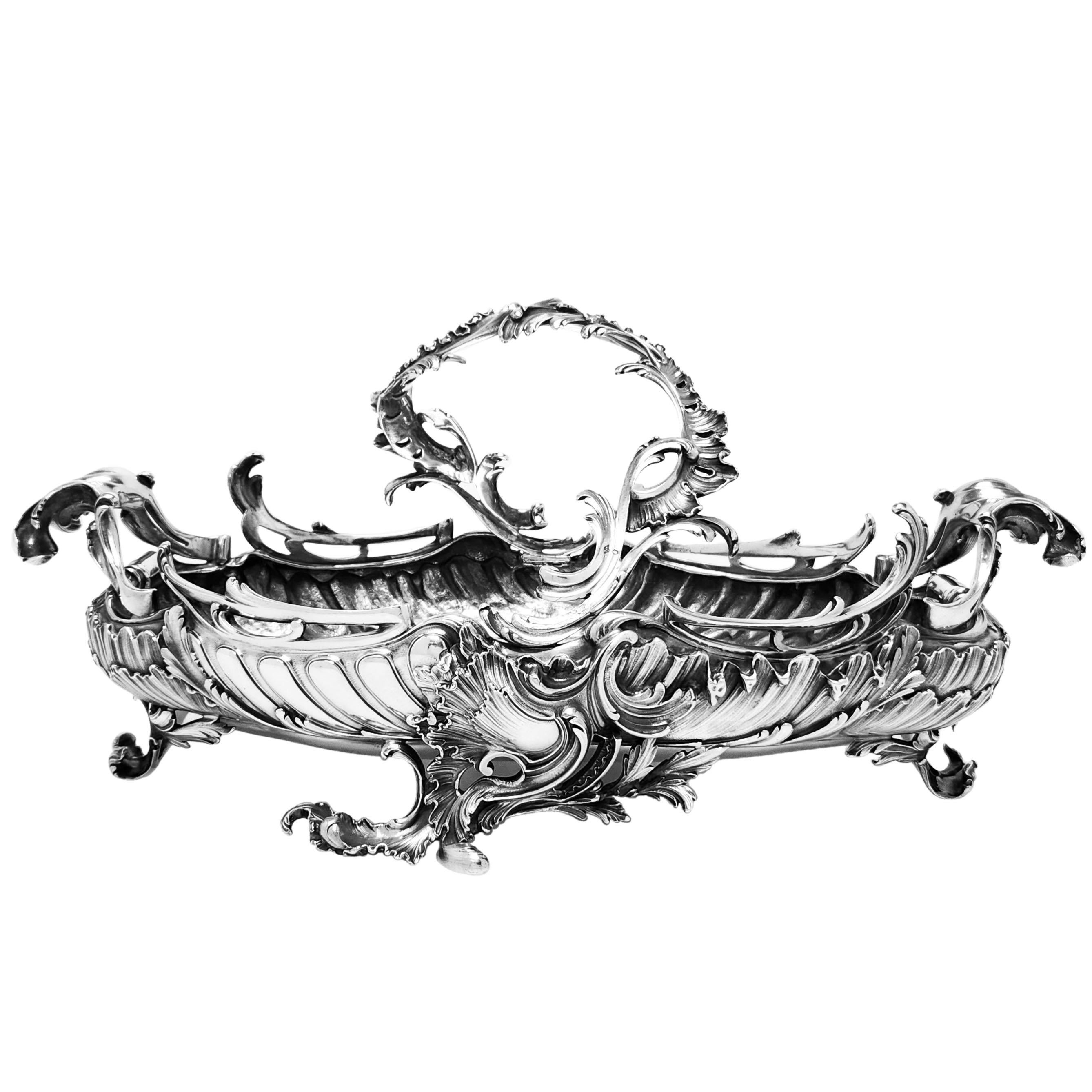 Un'imponente ciotola da centrotavola in argento francese dal design ornato in stile rococò che poggia su 4 piedi sagomati. Questo insolito cestino d'argento ha un manico asimmetrico incernierato. Il design rococò racchiude una sensazione di