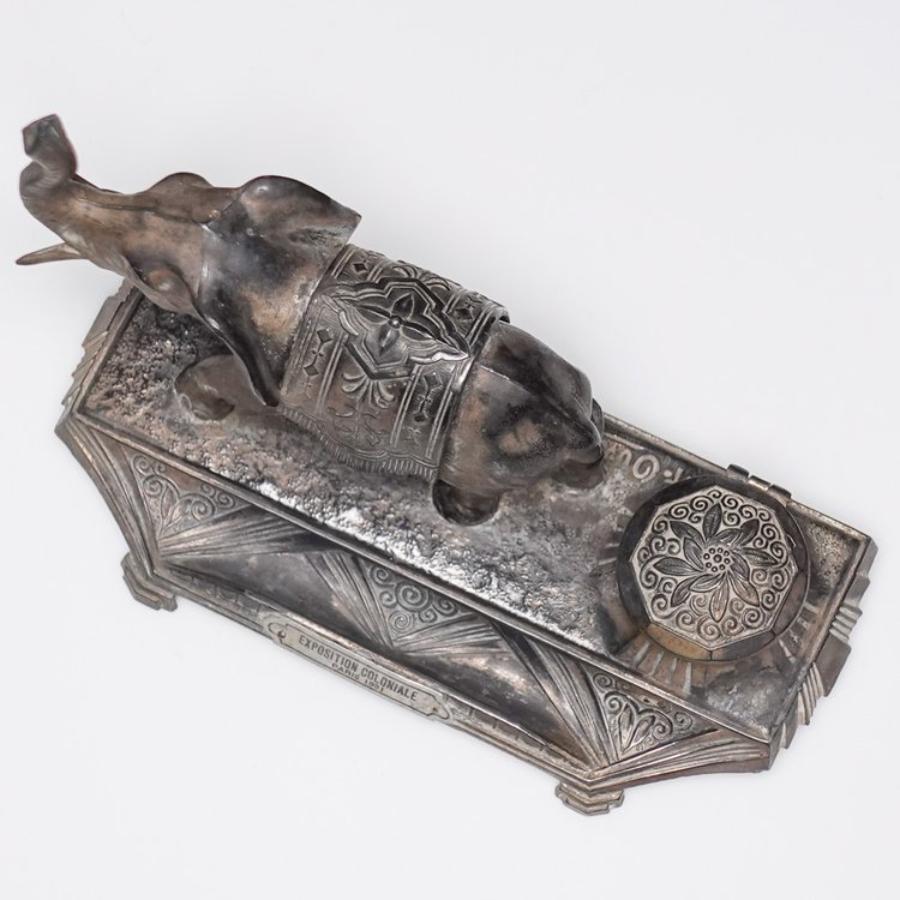 Here is a lovely antique French Spelter Inkwell signed “A. Ouvet”. This piece features a detailed spelter elephant with raised trunk. Enscribed “EXPOSITION COLONIALE PARIS 1931”. Missing inkwell insert.

Measures approx. 6.25”w x 2.75”d x