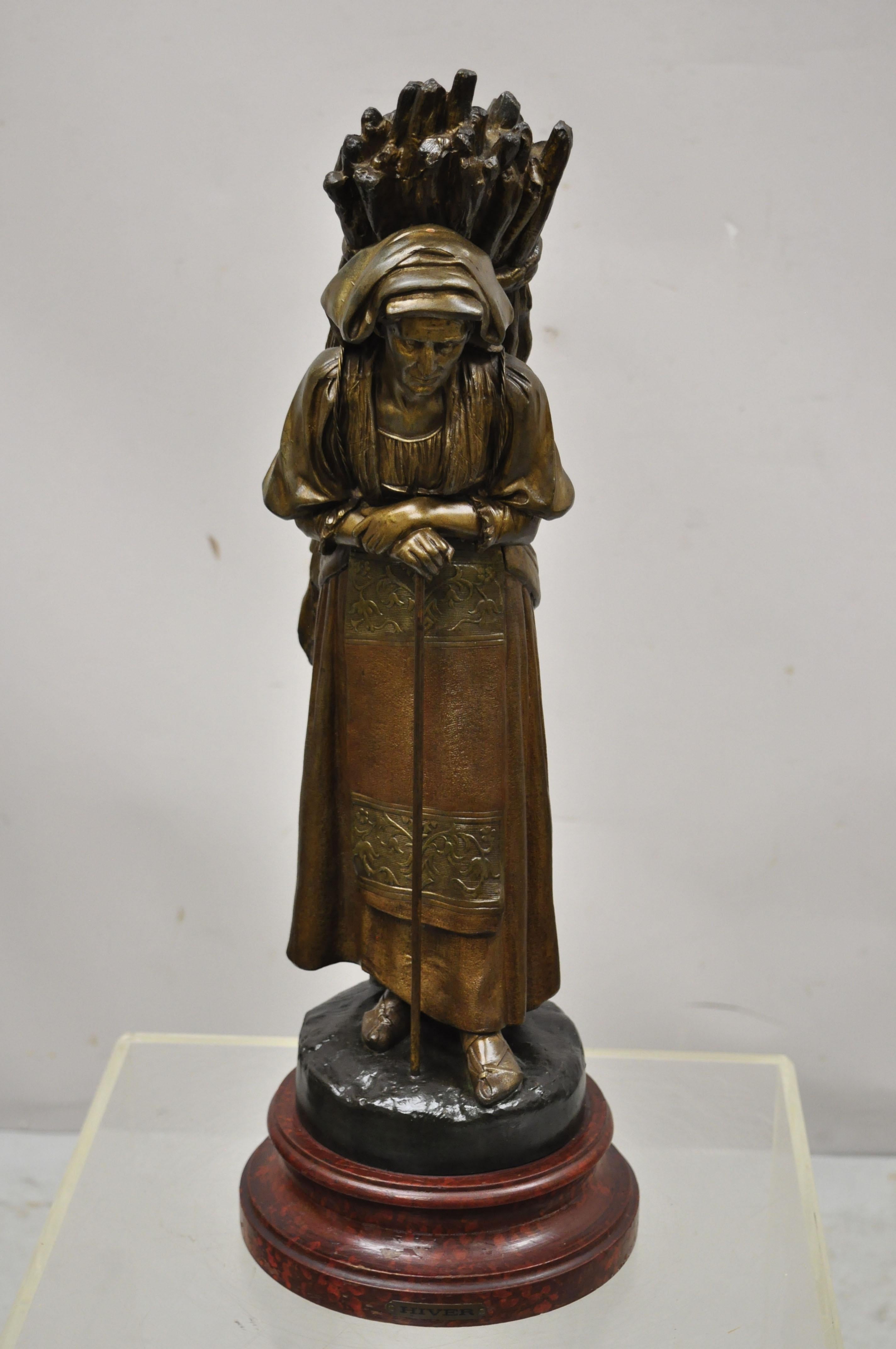Sculpture française ancienne en fonte Statue de femme portant un paquet de bâtons Causset Cadet ? Figurine de femme en métal fondu portant un fagot de bâtons sur le dos, socle en bois peint, étiquette en métal sur laquelle on peut lire 