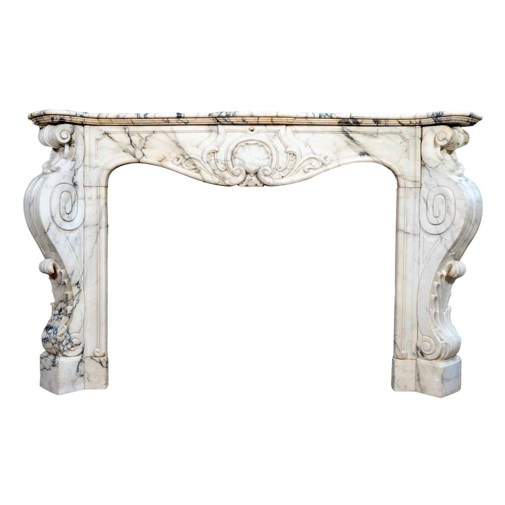 Elevate your living space with this Antique French Statuario Marble Mantel. Made from stunning Statuario marble, this 1850s reclaimed piece boasts striking black veining and intricate hand-carved detailing on the legs and center. The perfect blend