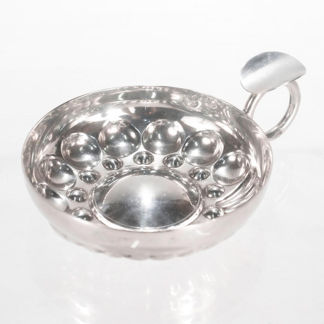 A fine antique French tastevin.

In sterling silver.

Having a bowl of shaped, typical from set with ring shaped handle and thumb tab.

Struck with a CP maker's mark in lozenge and with the 1st standard Minerva hallmark for .950 fine silver to the