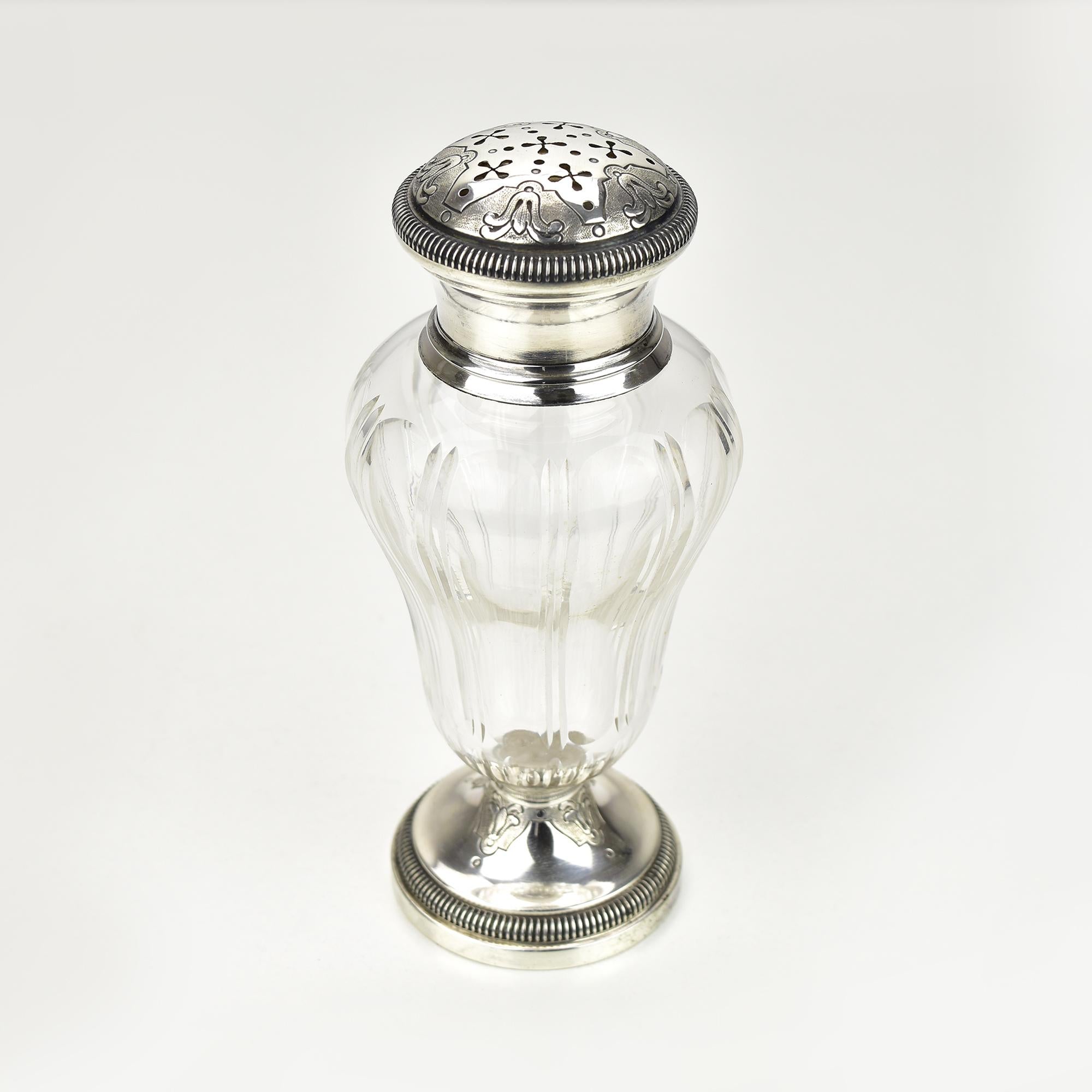 This exquisite antique French sugar shaker, also known as a muffineer or sprinkler, features elegant sterling silver mounts paired with fine cut crystal. 
The crystal body is crafted with a fluted pattern, adding a touch of sophistication, while the