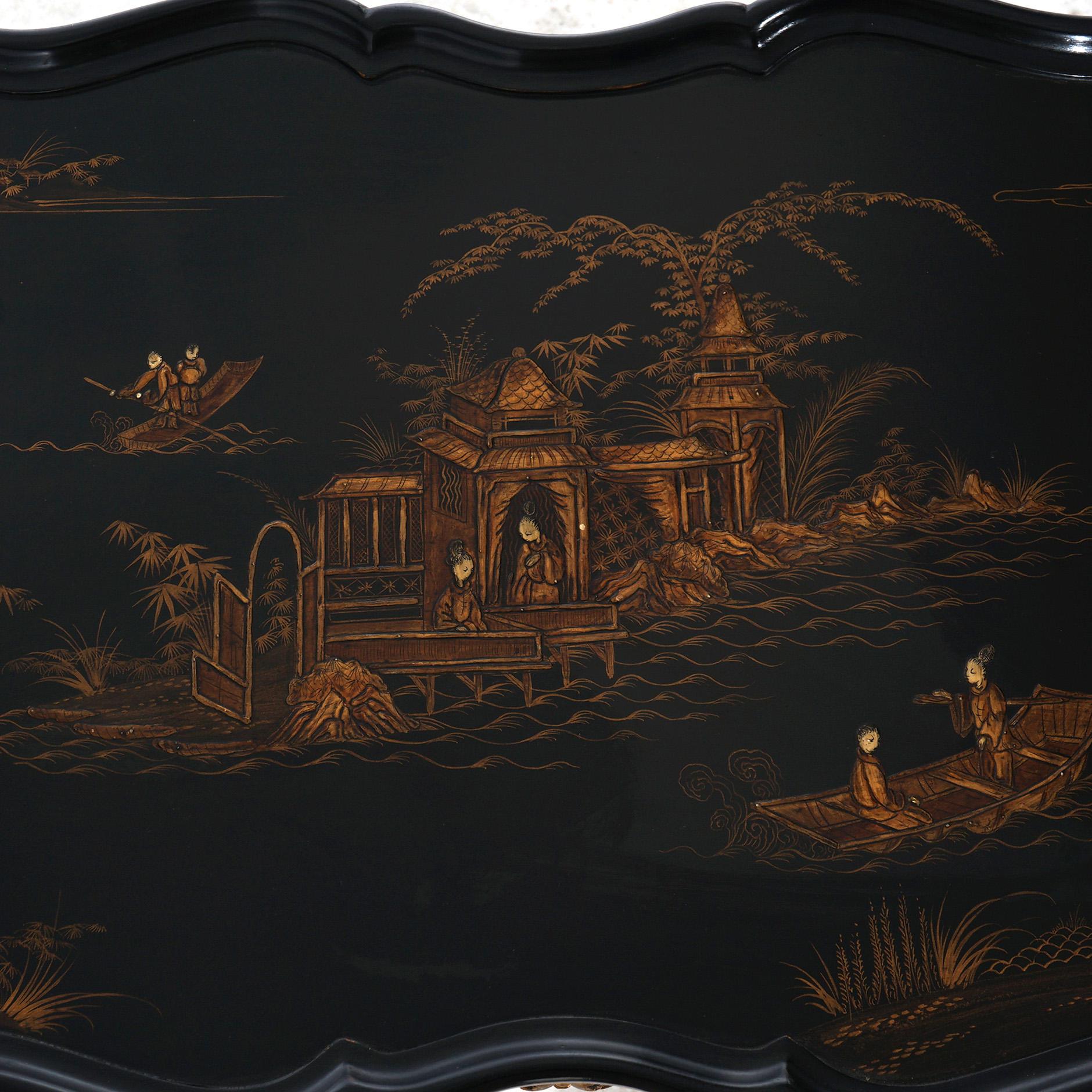***Ask About Reduced In-House Shipping Rates - Reliable Service & Fully Insured***
 An antique French style low tea table offers ebonized finish with Chinoiserie gilt countryside village scene; shaped top over case with pull-out trays over shaped