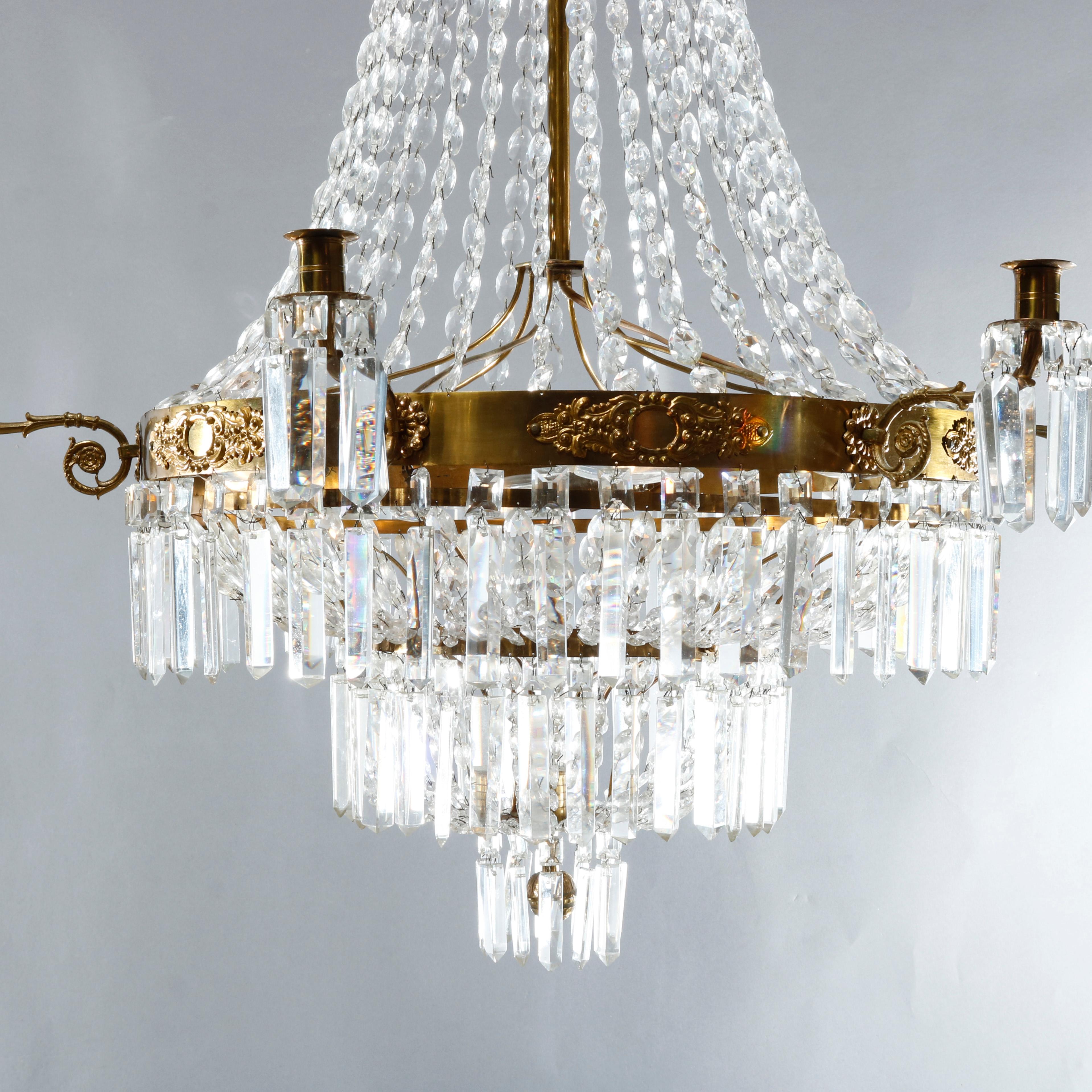An antique French style chandelier offers tiered wedding cake form with bronzed metal frame having foliate elements on collar with scroll form arms terminating in candle lights with strung and cut crystals throughout, 20th century.

Measures: 46