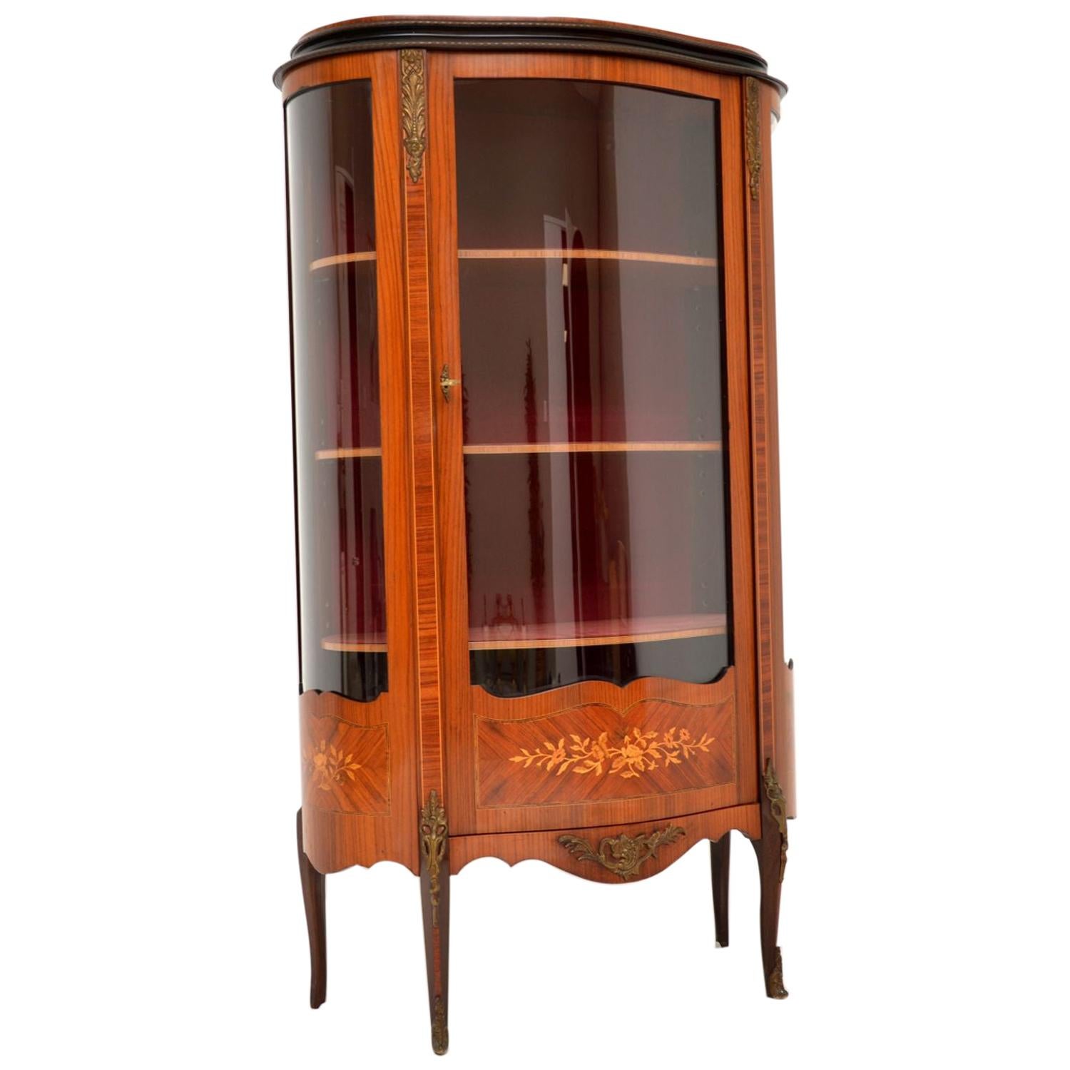 Antique French Kingwood display cabinet with three floral marquetry panels at the base and various other inlays.

It has a curved front and gilt bronze mounts. The inside lining is a kind of plush velvet, which is original to this item and is