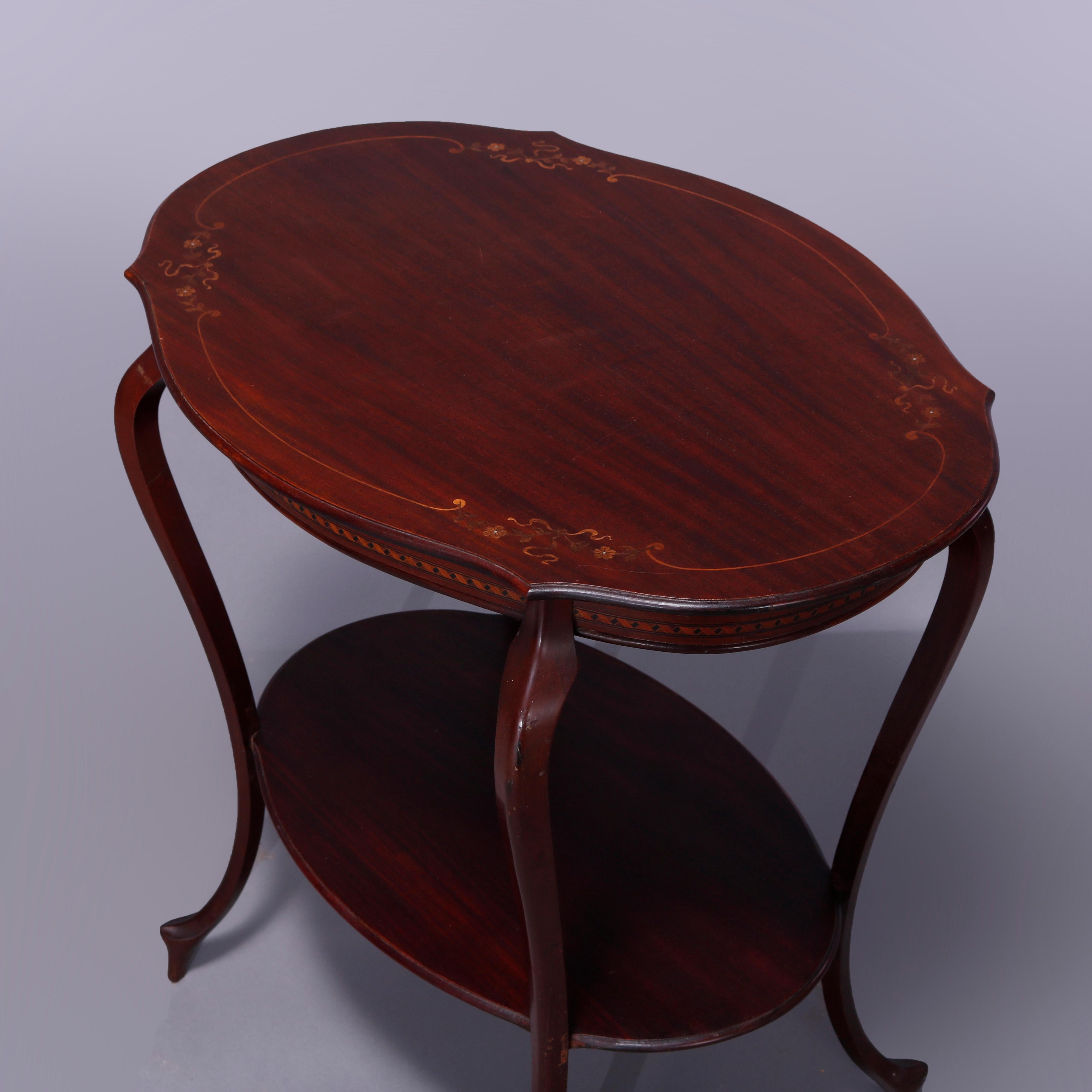 An antique French style parlor table offers mahogany construction with shaped top having satinwood inlaid floral and foliate marquetry inlay, raised on cabriole legs with lower display shelf, c1900

Measures - 30.25
