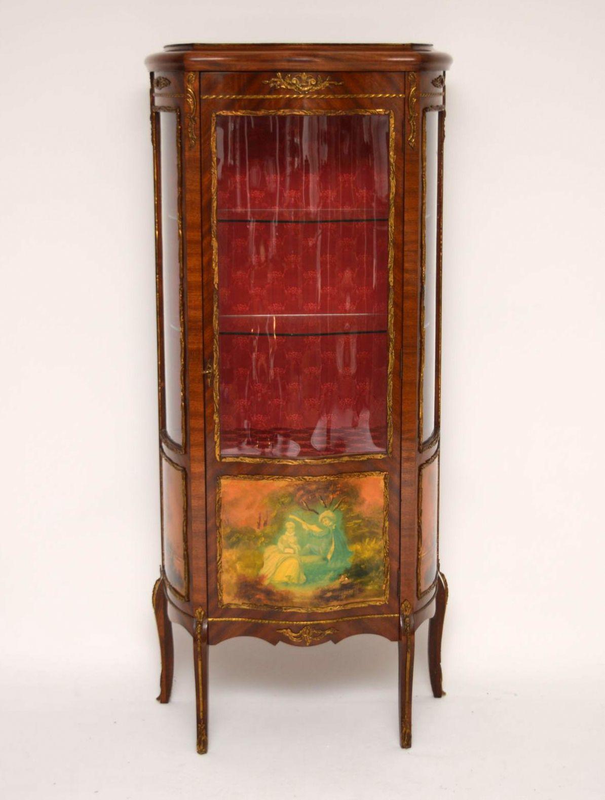 Antique French style serpentine fronted display cabinet of fairly small proportions, which I would date to 1930s-1950s period. It’s predominately mahogany, with three decorative panels & is mounted with gilt metal. This cabinet is in good original