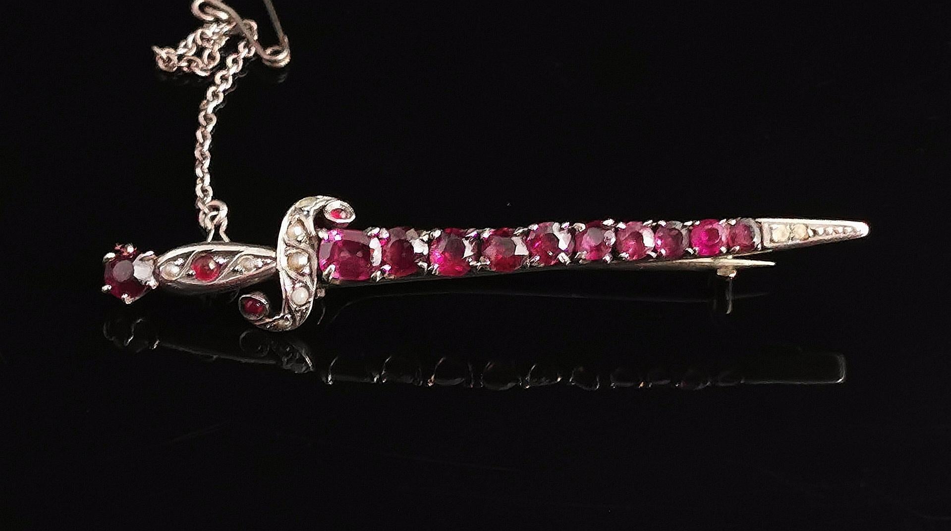 A stunning antique French sword or dagger brooch.

Set in silver this brooch has a beautiful design with a scrolling handle and twinkling gem set blade.

It is filled with pretty rhodolite garnets, all round apart from the Garnet to the top of the