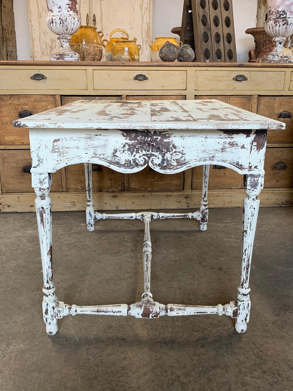 A beautiful decorative French table from the early 20th century. With lovely decorative wood carvings and original worn paint. Circa 1900 in date.