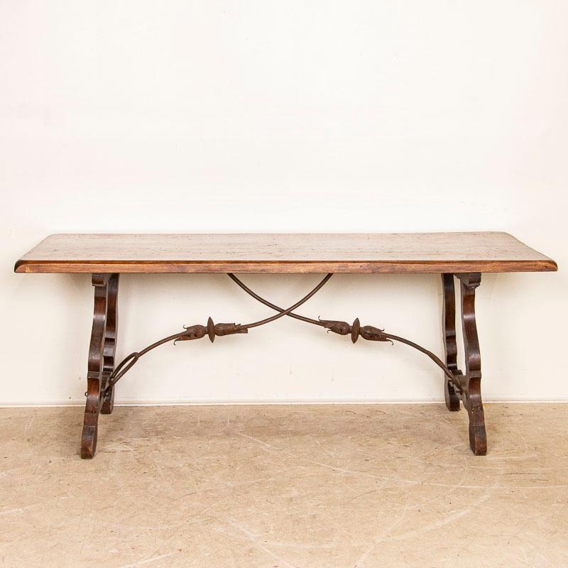 This fascinating 6' table holds visual intrigue due to the carved wood and iron base. Notice the carved scalloped and curved details accented and supported by the wrought iron scroll work of the unique base. Please examine photos to understand the