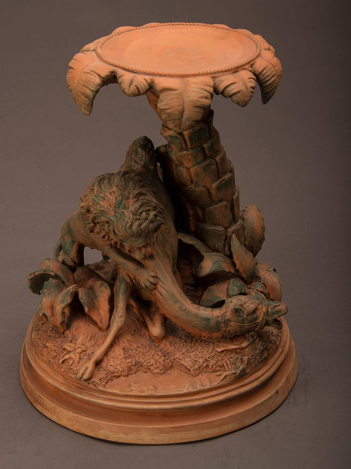 An antique French terra cotta sculpture featuring a camel and lion in a death duel from France, circa 1900. This ferocious depiction of a desert fight around a palm tree at an oasis is full of immediacy and skillfully conveys the rapidity of