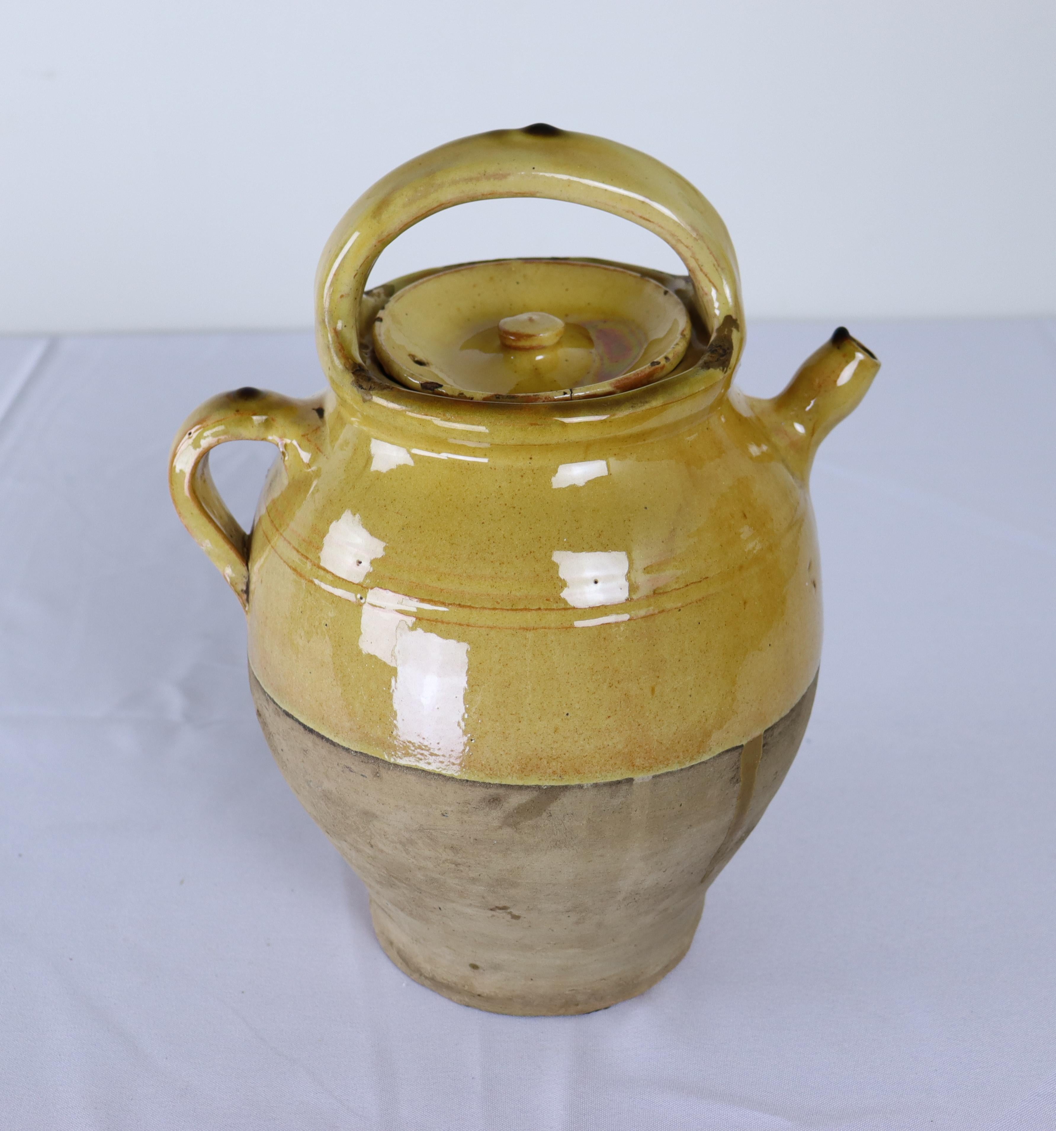 A French Antique terra cotta water jug or cruche in traditional mustard yellow glaze.  Festooned with desirable drips and glaze pooling.  Very hard to find with lid intact.  Some wear around the rim, shown,  but no chips.  A find!