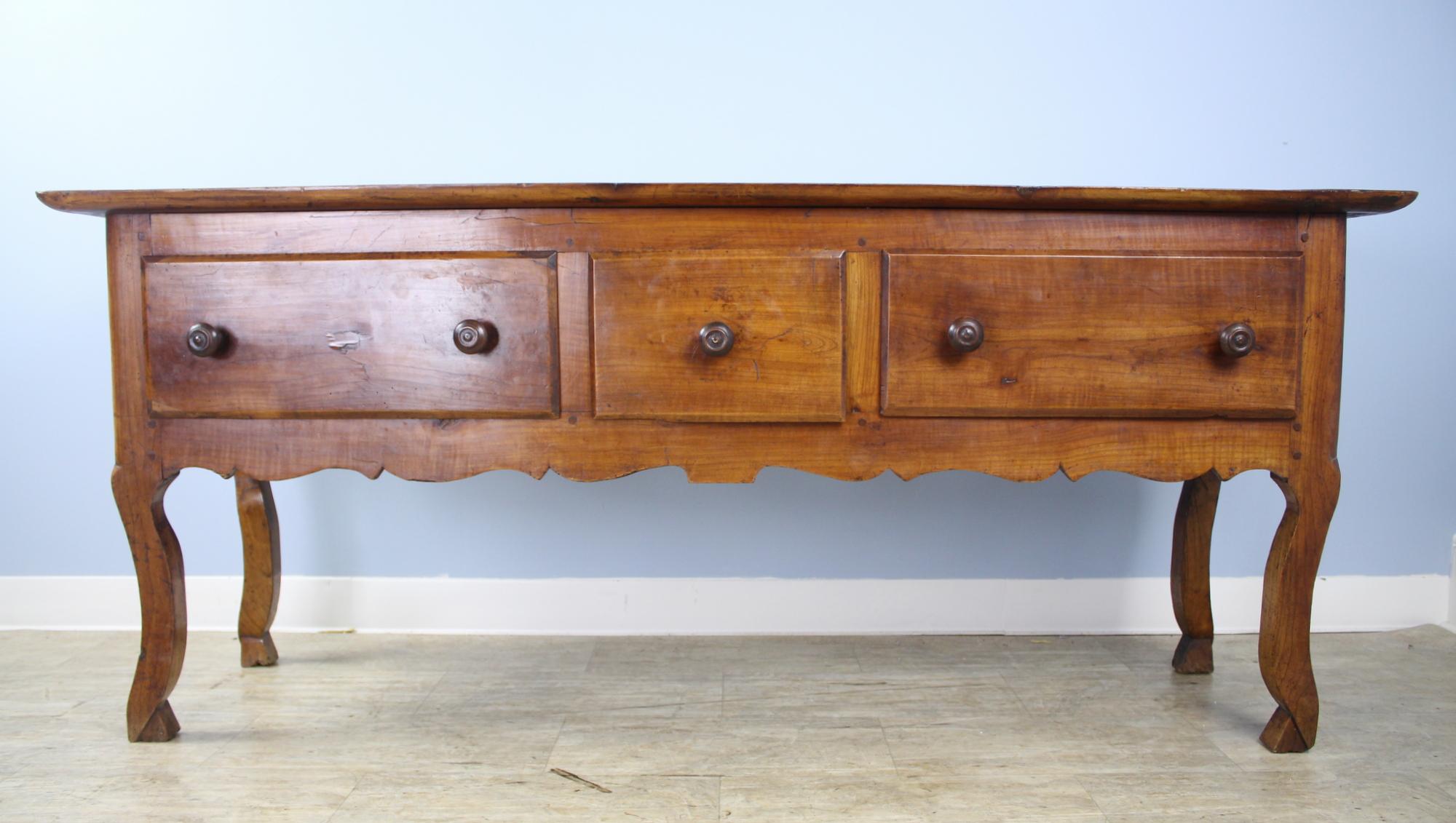 A stylish server or sideboard with three deep drawers, and a lovely carved apron. Nice depth the allow space for passing through or pushing back one's dining chair. Graceful cabriole legs and hoof feet complete the look.  The back side of this