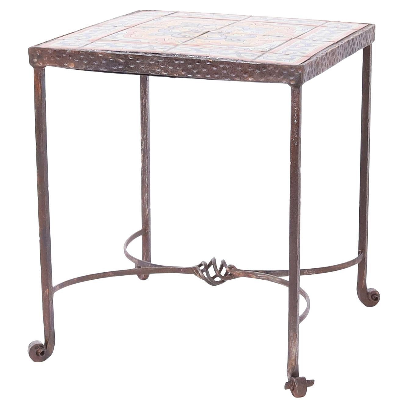 Impressionnante table d'appoint en fer à plateau carré de Bushere & Son. Ayant des carreaux avec des fleurs de lys stylisées dans des couleurs méditerranéennes et modelées selon le style de l'ancienne Californie. Le tout sur une base forgée à la