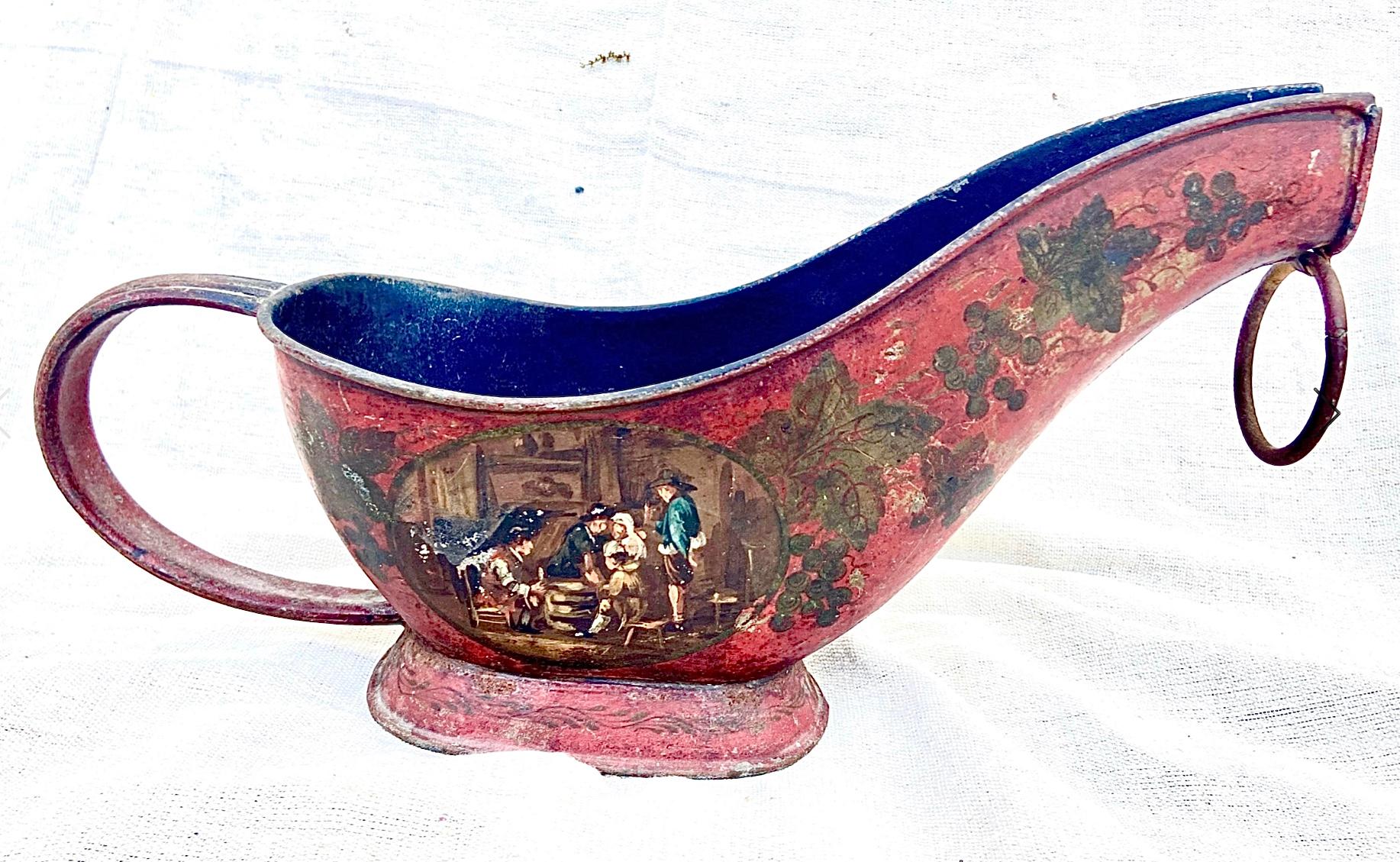 Antique French tole wine bottle holder. Background color is a deep red with painted on grapes, leaves, and French tavern scenes. Caddy has a large handle and ring at spout to enhance pouring of wine.