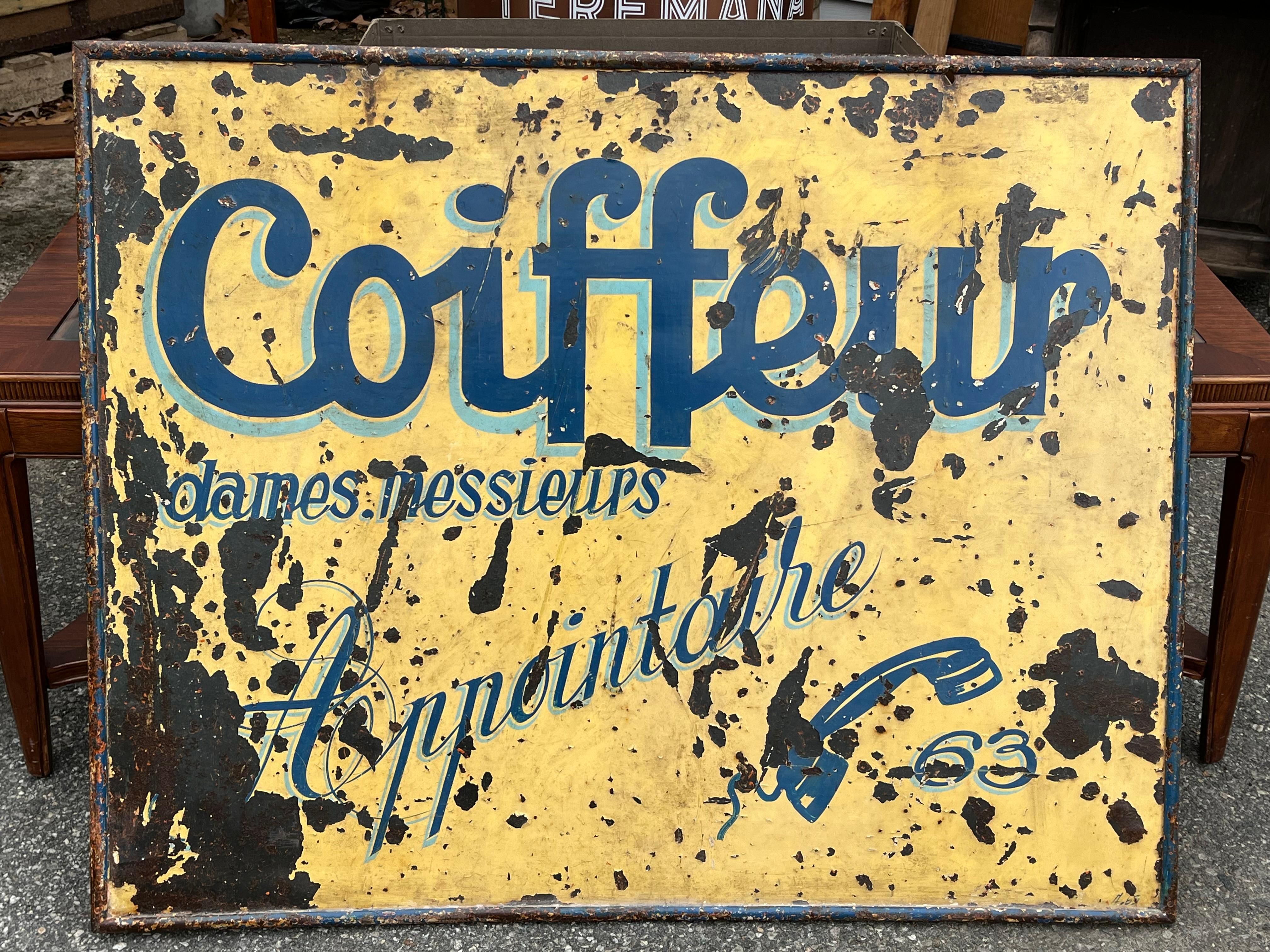 A 1930’s era trade sign in sheet metal with yellow and blue enamel decoration advertising a Coiffeur with a two digit phone number. Great decoration for a salon or barber shop. 