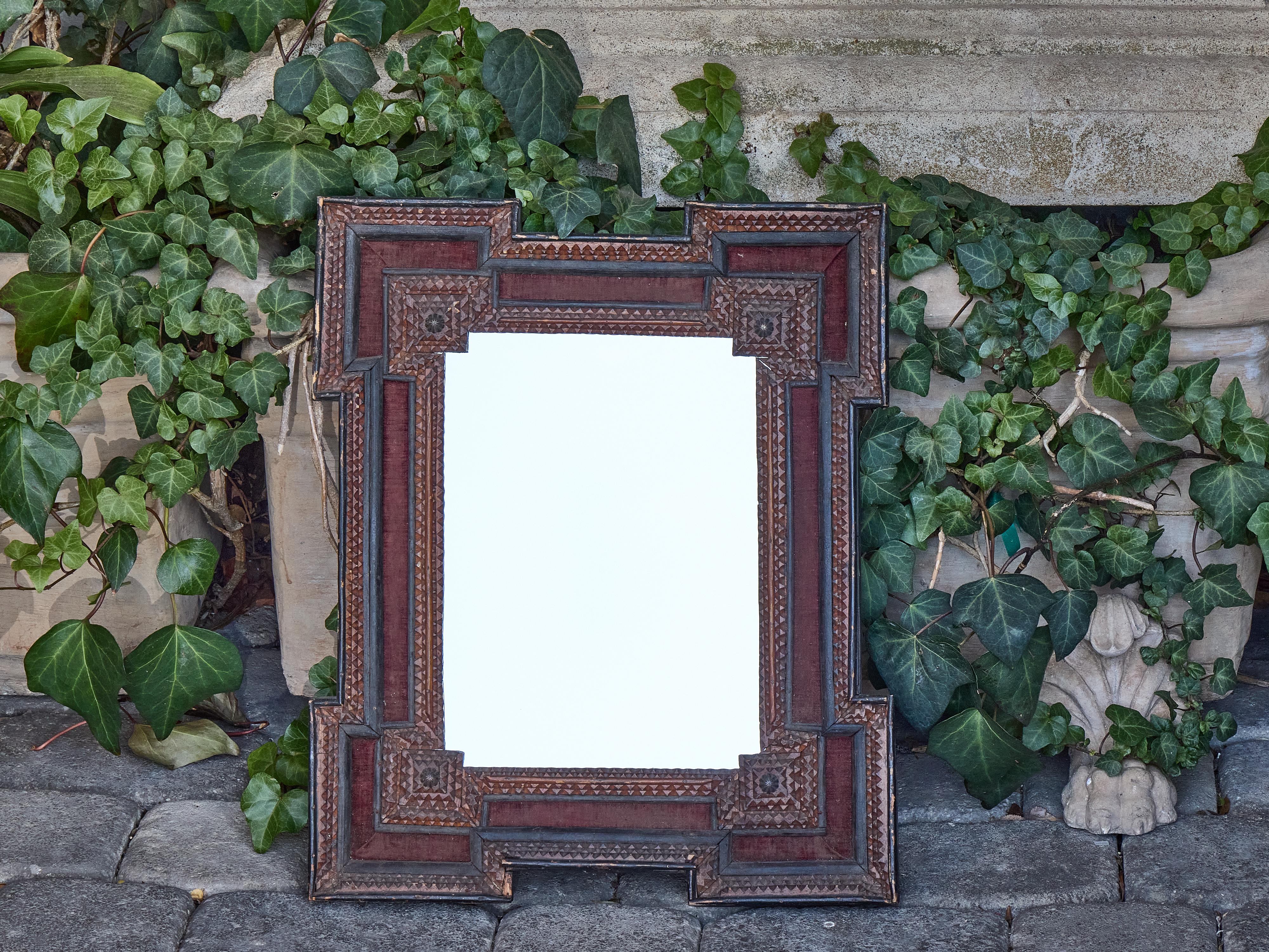 Miroir français du début du 20e siècle, fabriqué à la main vers 1900 avec des boiseries géométriques complexes et des coins en escalier qui encadrent le verre avec un caractère graphique. Le cadre est profondément dimensionnel et présente des