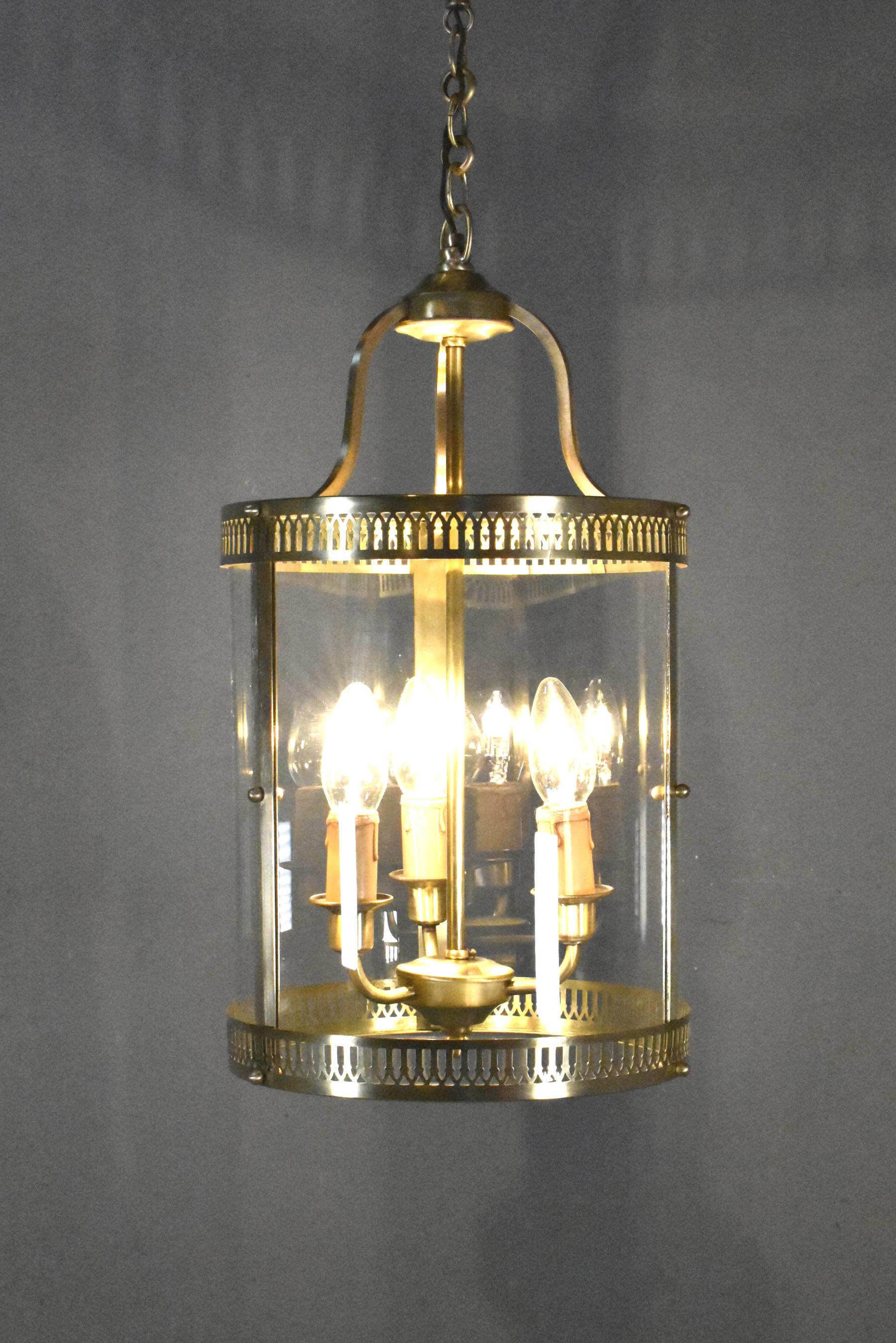 Antique French Triple Light Hall Lantern in Brass 

This attractive round hall lantern features pierced brass continuous rings at the top and bottom that hold three curved clear glass panels. 

Descending from the polished ceiling rose there is a