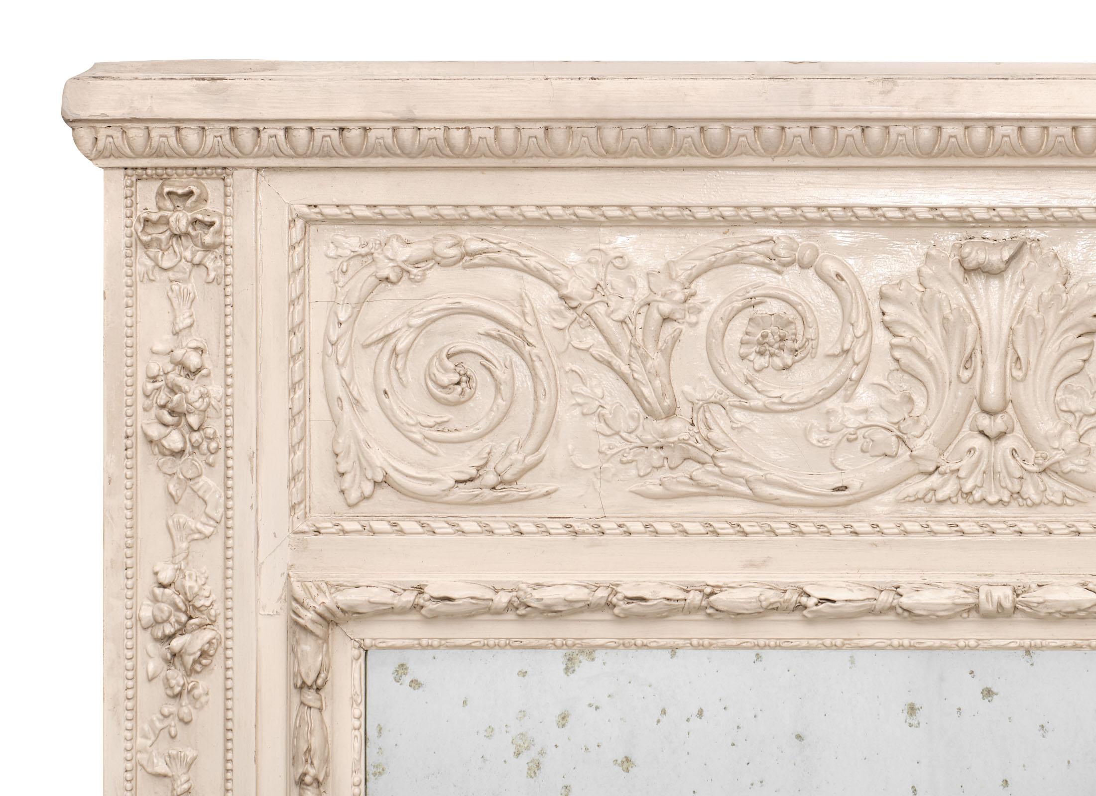A French antique trumeau with hand carved details and a painted and patinated finish. This piece features the original Mercury mirror, beautifully aged. We loved the large size, the floral details and scrolls on the fronton.