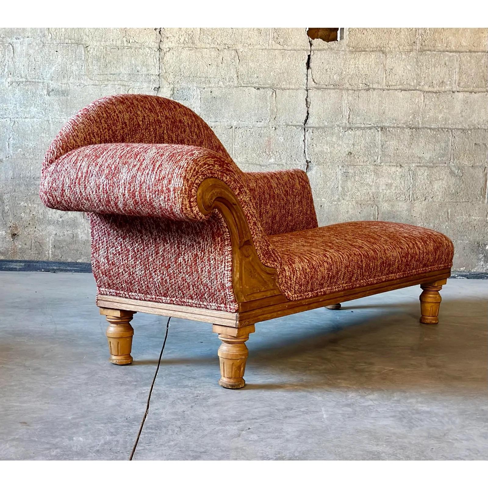 An Antique French Daybed. Recently recovered in a variegated red/burnt orange Italian boucle. The asymmetrical lines and intricate wood detailing make this a true beauty.