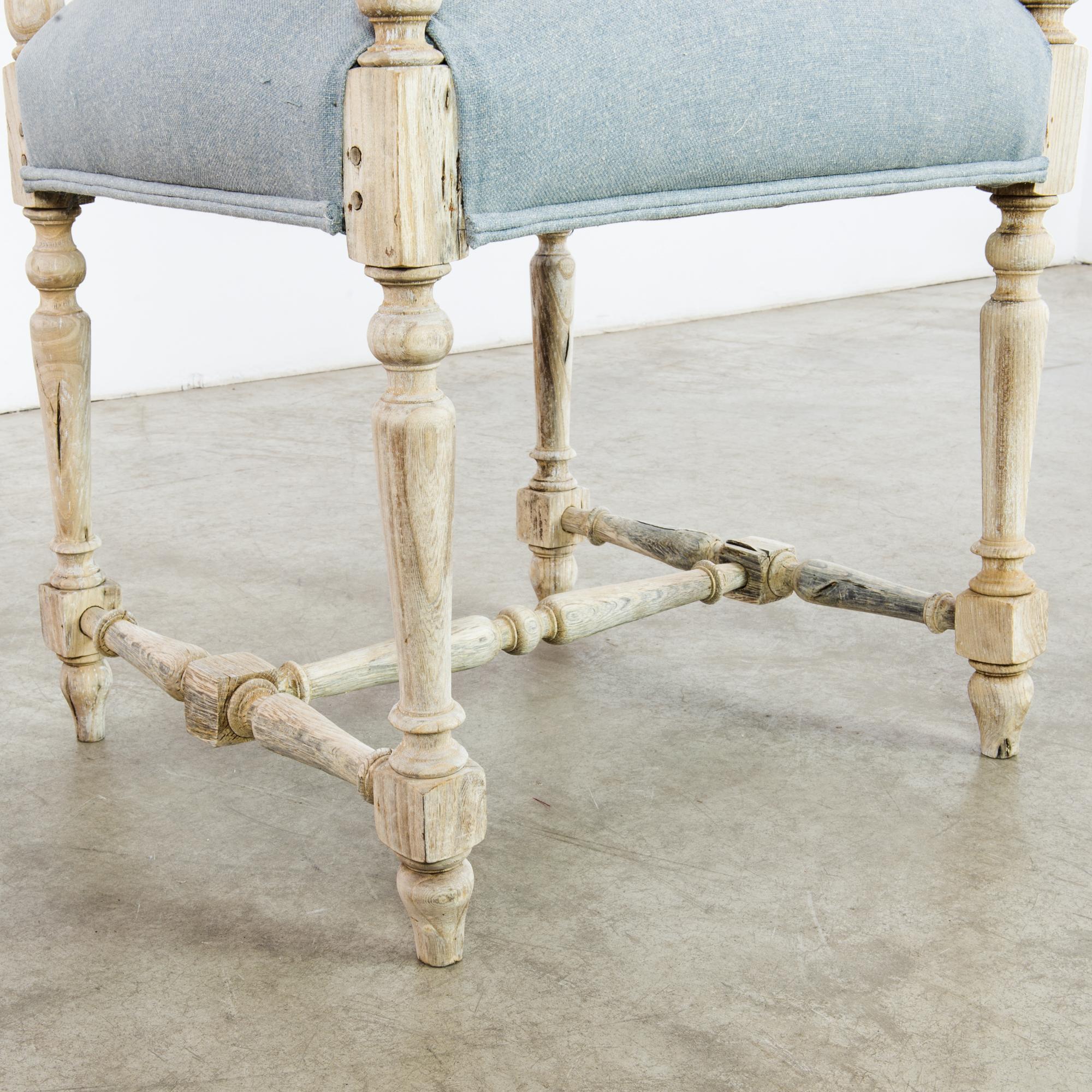 This antique wooden armchair with intricate carvings on the back and armrests was made in France. The captivating details from the spires on the back to the turned legs impart an old-world charm. Refurbished in our atelier with a dusk blue