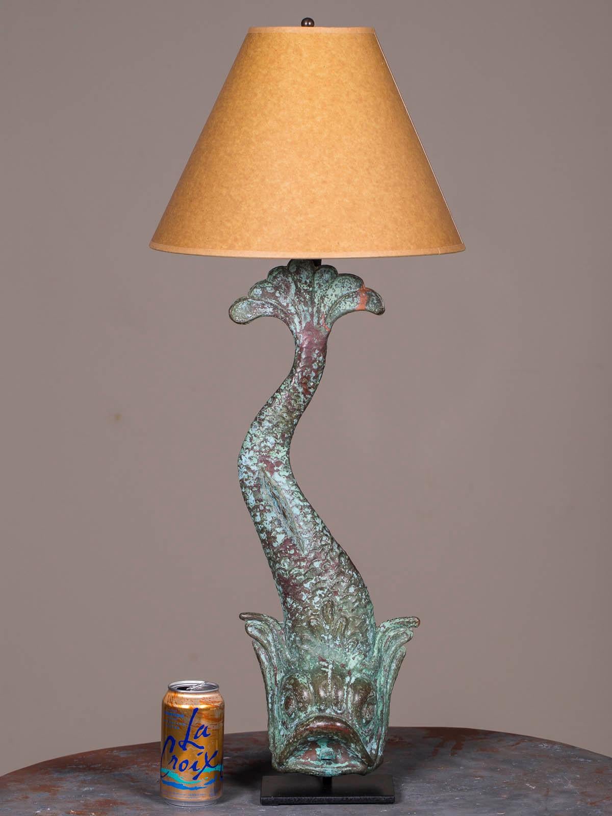 A marvelous antique French copper dolphin waterspout custom lamp from a wall fountain circa 1895 retaining its original finish now mounted on a custom iron stand and topped with a bronzed paper shade. Please notice the sensuous curve of the dolphin