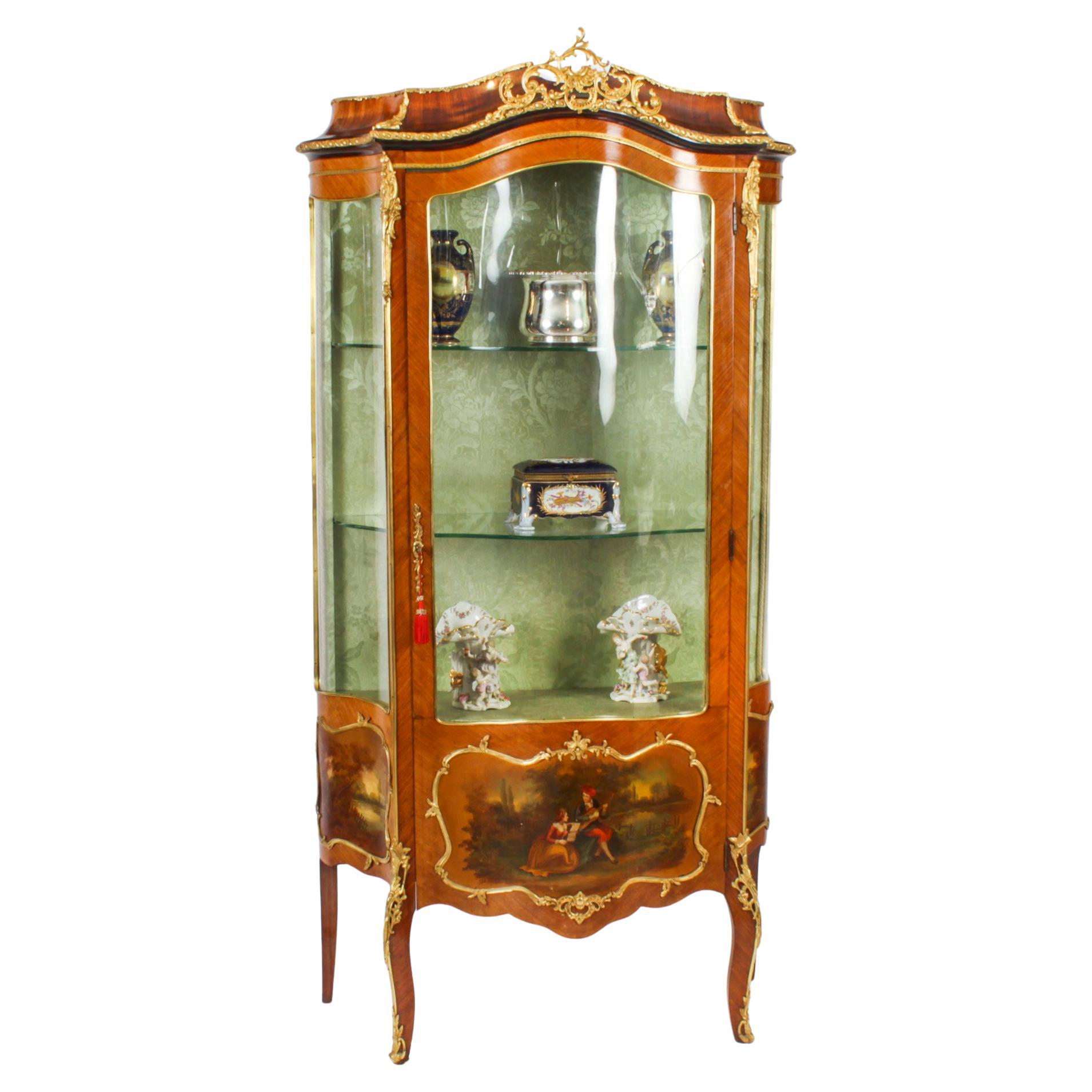 This is a stunning antique French Louis XV Revival wood and ormolu mounted Vernis Martin display cabinet, circa 1880 in date.
 
The cabinet features a shaped top with impressive and ornate ormolu mounts. The body is serpentine shaped with a glazed