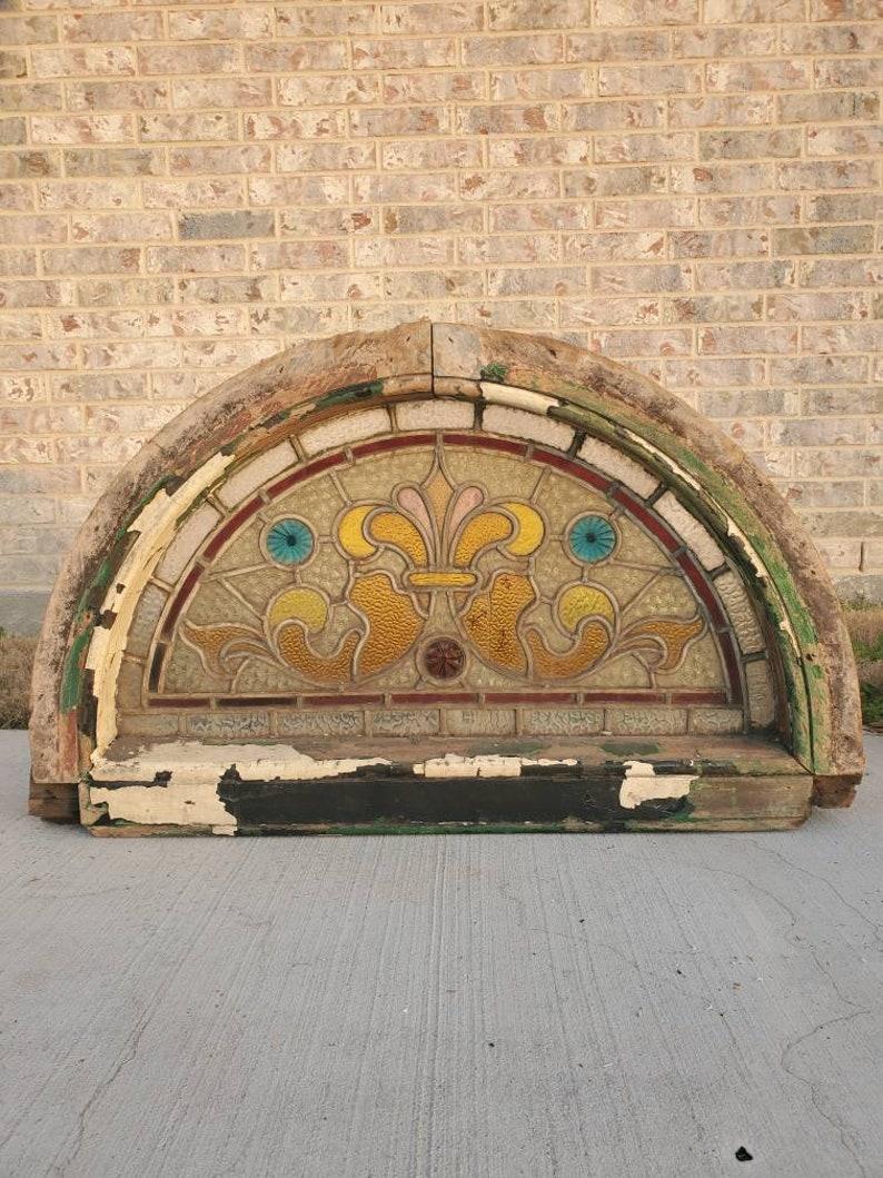 An absolutely beautiful French Victorian antique stained glass panel arched transom window that must be viewed in person to truly capture the stunning vibrant colors, rich texture and sophisticated styling. 

This exterior architectural salvaged