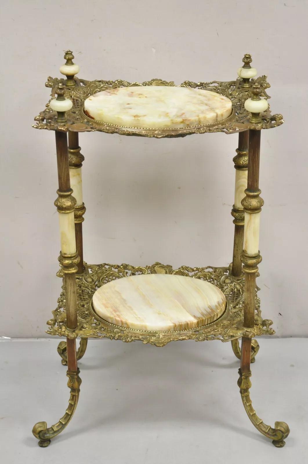 Antique French Victorian Bronce 2 Tier Onyx Stone Plant Stand Accent Table. El artículo presenta un marco figurado de bronce con figuras masculinas y femeninas, 2 superficies ovaladas de piedra de ónice con remates de ónice, mesa antigua muy bonita.