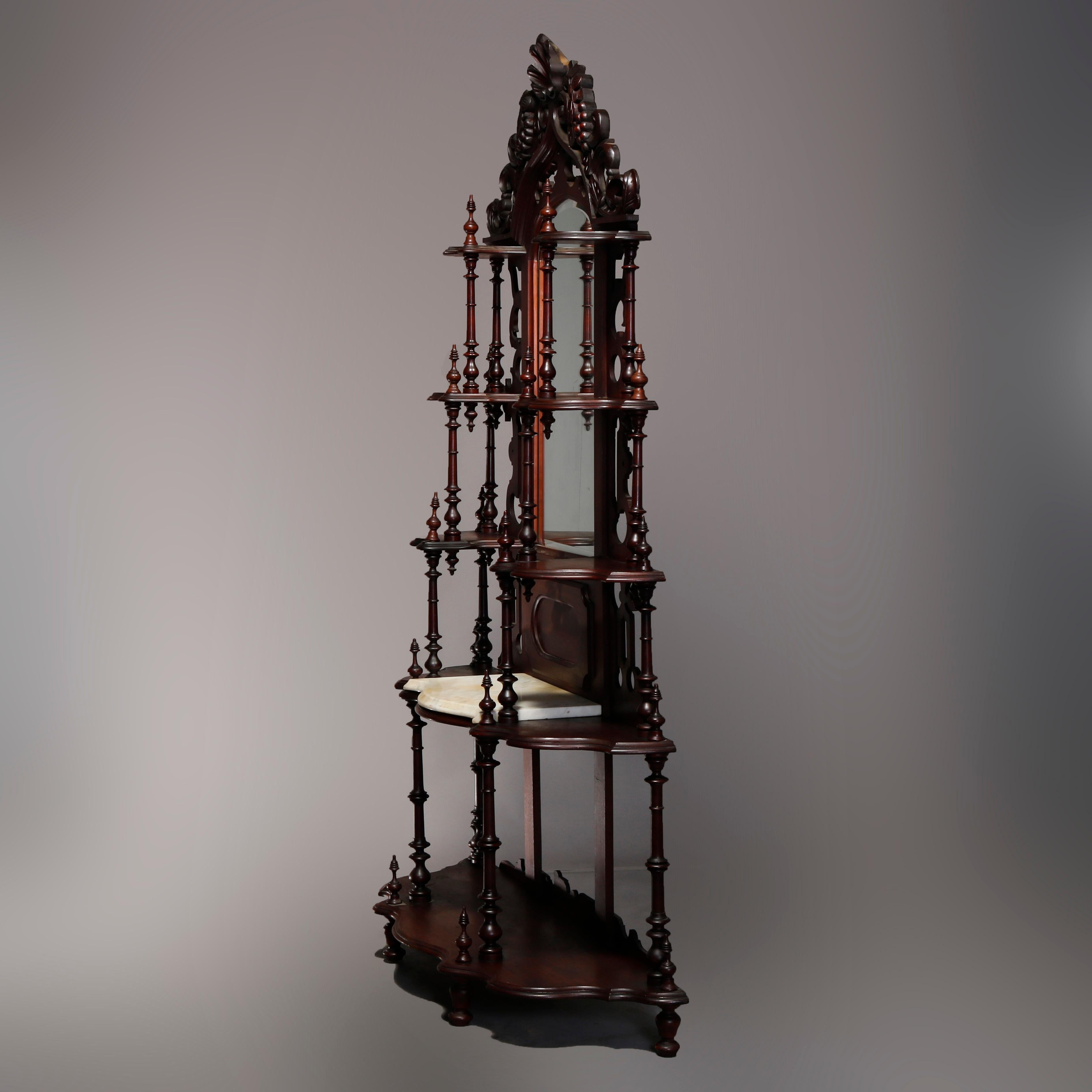 An antique French Victorian étagère offers walnut construction with arched mirror having pierced frame having carved shell crest with flanking grape and leaf scrolled elements, tiered and shaped side displays, lower marble shelf, and raised on